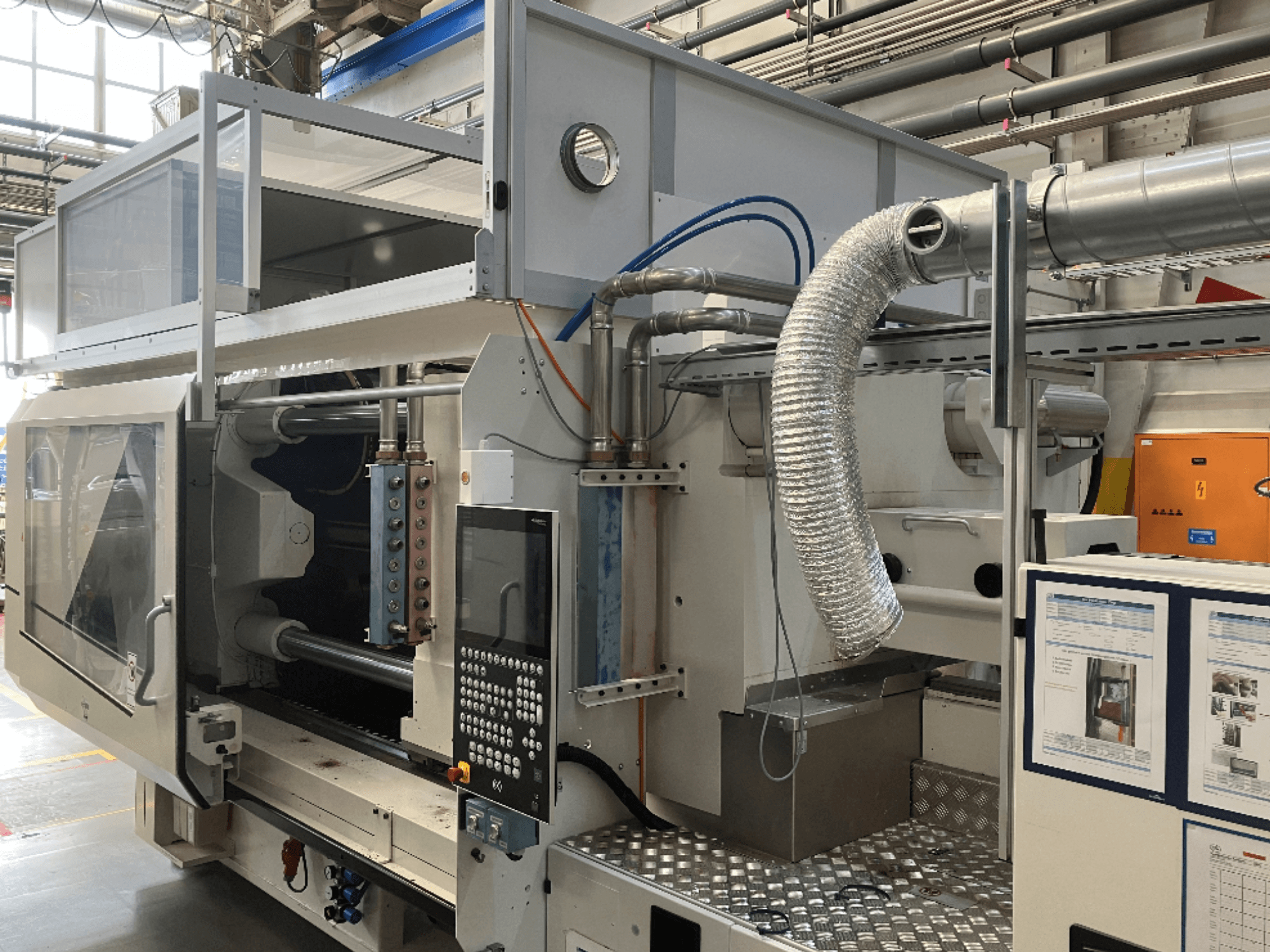 Machine industrielle de la marque X, vue de côté montrant le panneau de commande, les conduits et les composants de la machine dans une usine.