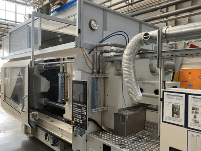 Machine industrielle de la marque X, vue de côté montrant le panneau de commande, les conduits et les composants de la machine dans une usine.