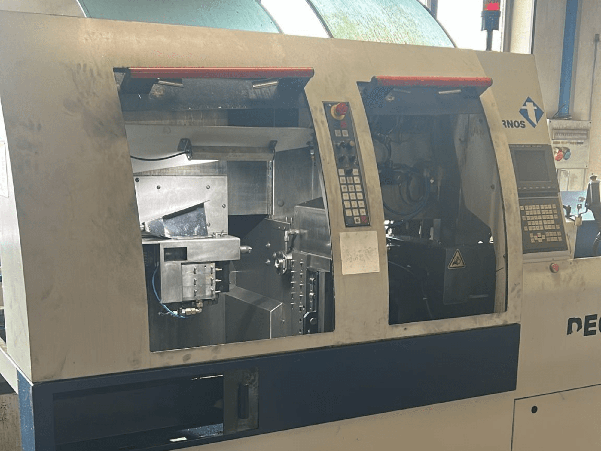 Alt text : Vue de face d'une machine de tournage TORNOS Deco 13 b de type suisse, avec panneaux de commande et composants internes visibles.