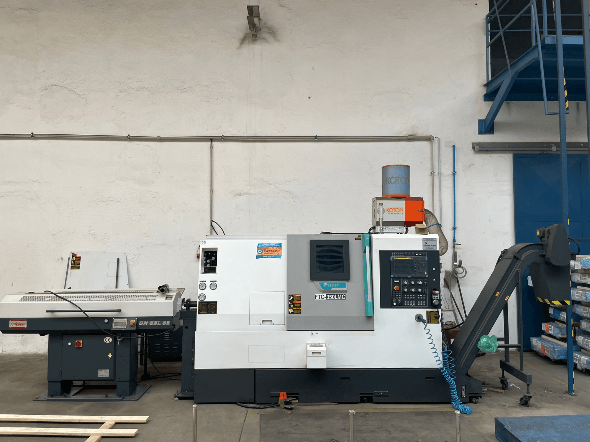 Tour horizontal Feeler FTC 350 LMC dans un atelier, montrant le panneau de commande et les lignes d'alimentation des outils. Vue de côté.