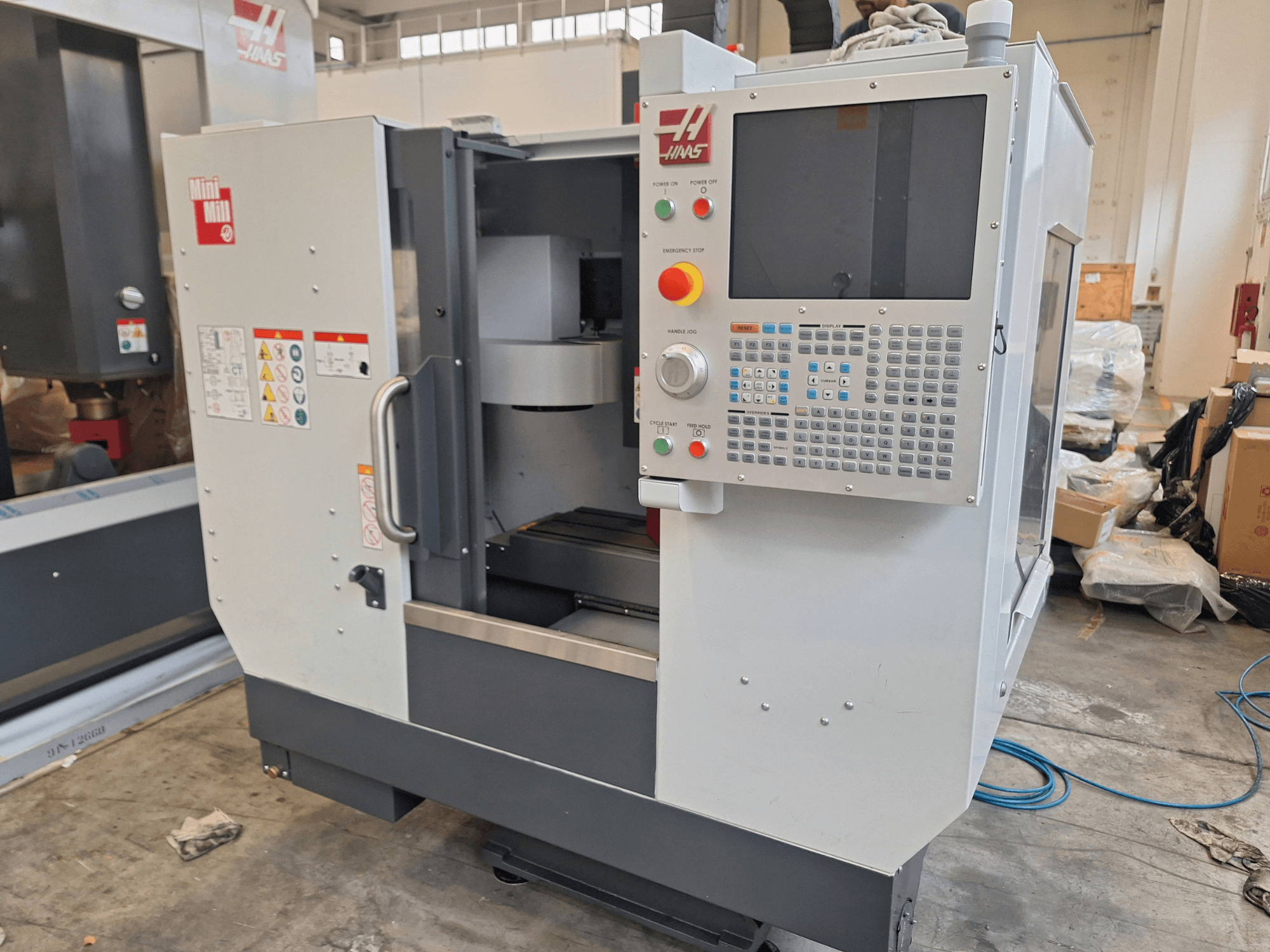 Centre d'usinage vertical HAAS Mini Mill vu de face, doté d'un panneau de commande avec des boutons et un écran d'affichage.