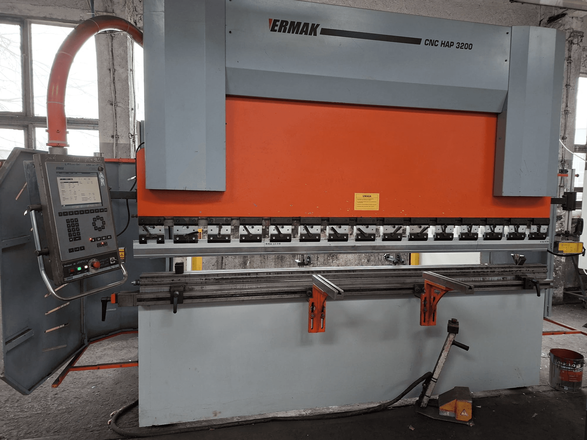 La presse plieuse Ermak CNC HAP 3200, vue de face, présente un corps orange et gris, un panneau de commande avec affichage numérique et des pinces réglables.