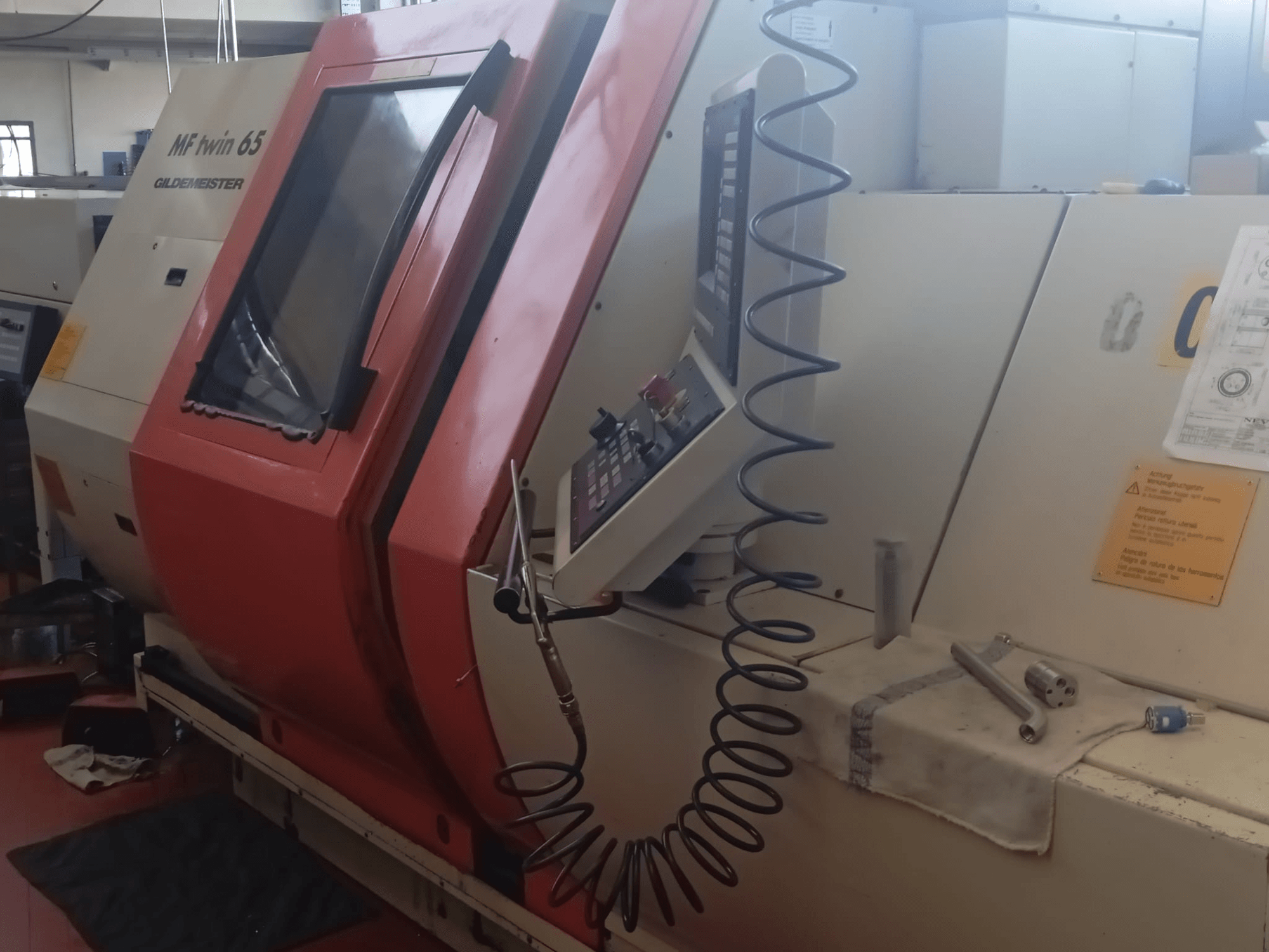 Machine MF twin 65 Gliedemeister orange et blanche, vue de face, avec panneau de commande et outils sur un chiffon.