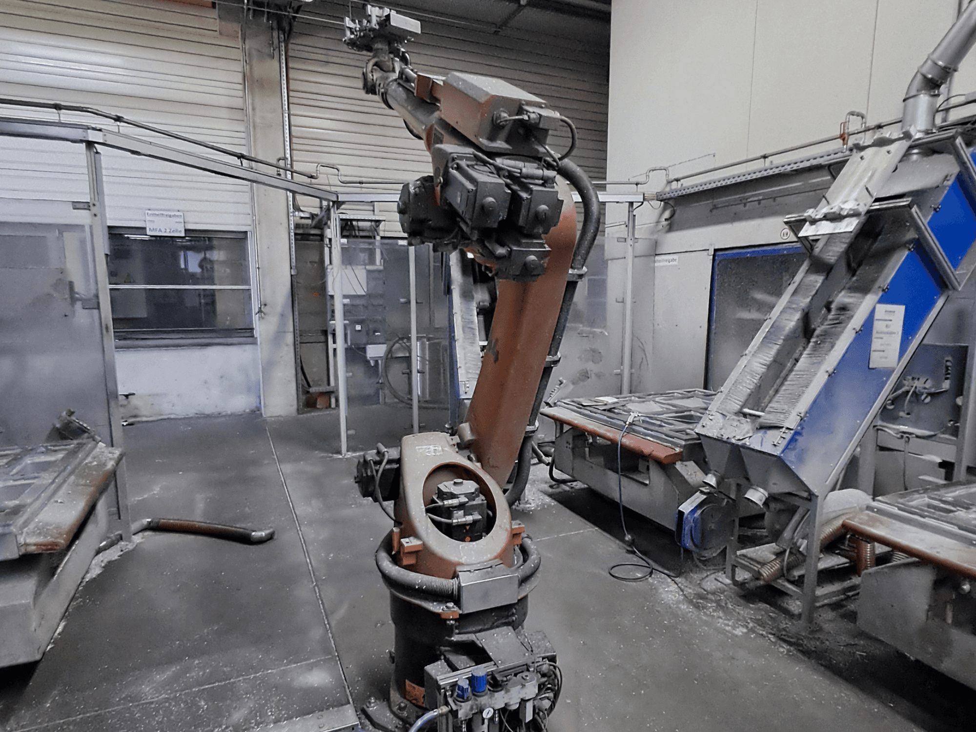 Bras robotisé KUKA KR 30L16-2 dans un atelier, vue de face, avec de la poussière visible et des machines en arrière-plan.