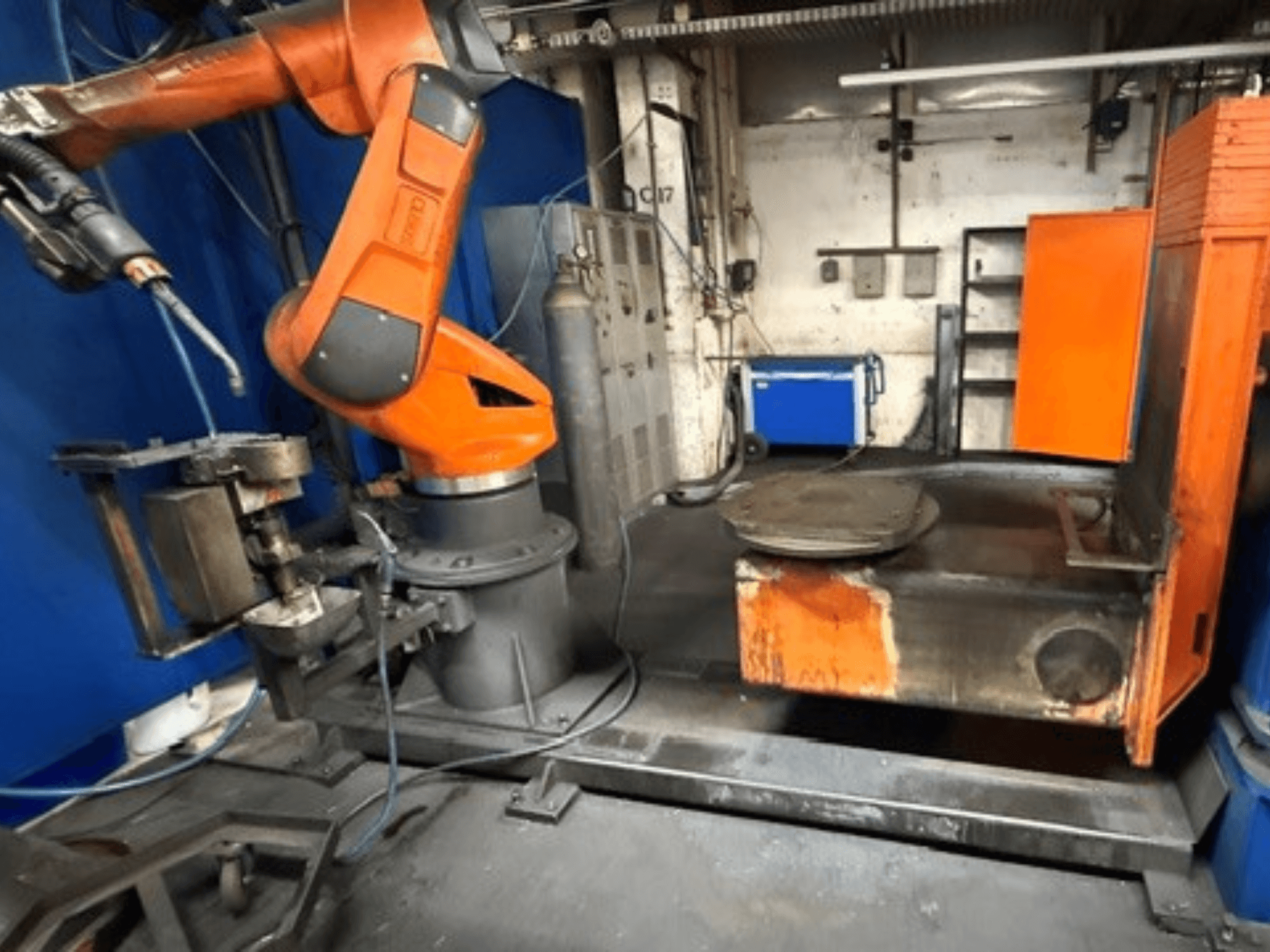 Robot de soudage CLOOS C50 vu de face, doté d'un bras robotisé orange et d'une table de travail métallique.