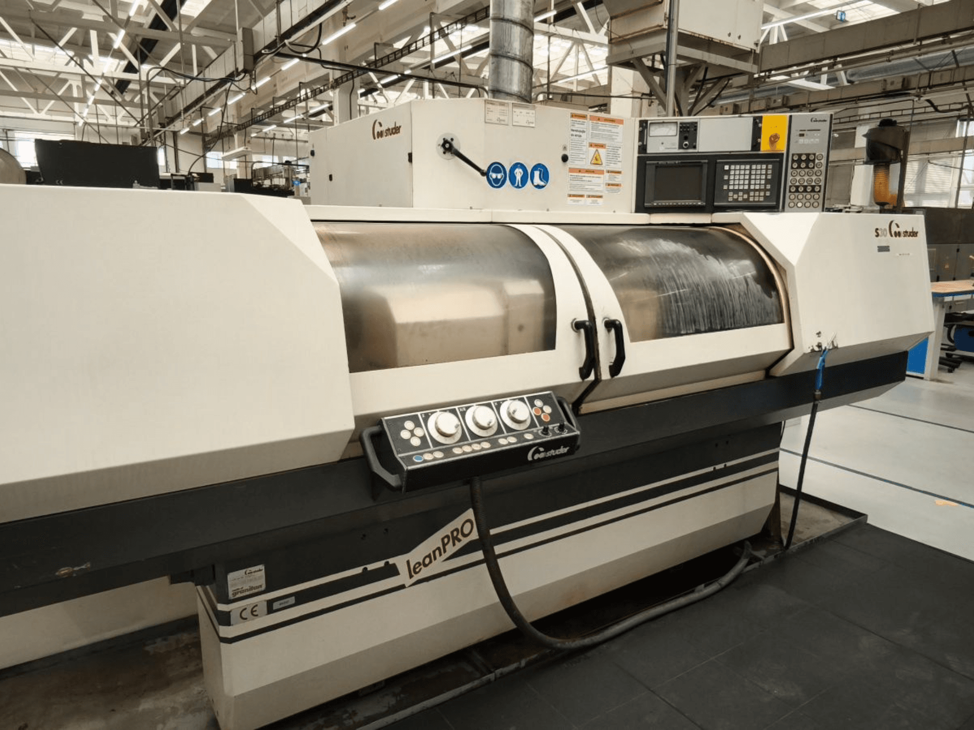 Rectifieuse cylindrique STUDER S30 LEAN PRO, vue latérale, montrant le panneau de commande et le couvercle de la meule dans un environnement industriel.