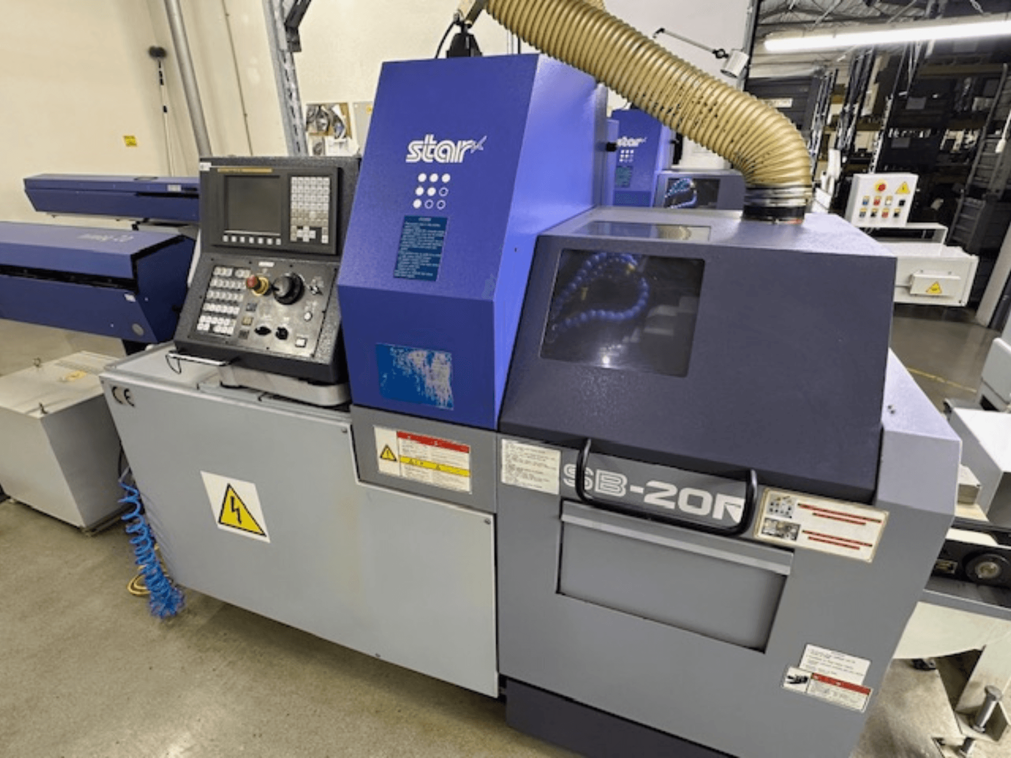Tourneur suisse Star SB-20R type N, vue de face, avec panneau de commande, tuyau d'aspiration et symboles de danger visibles.