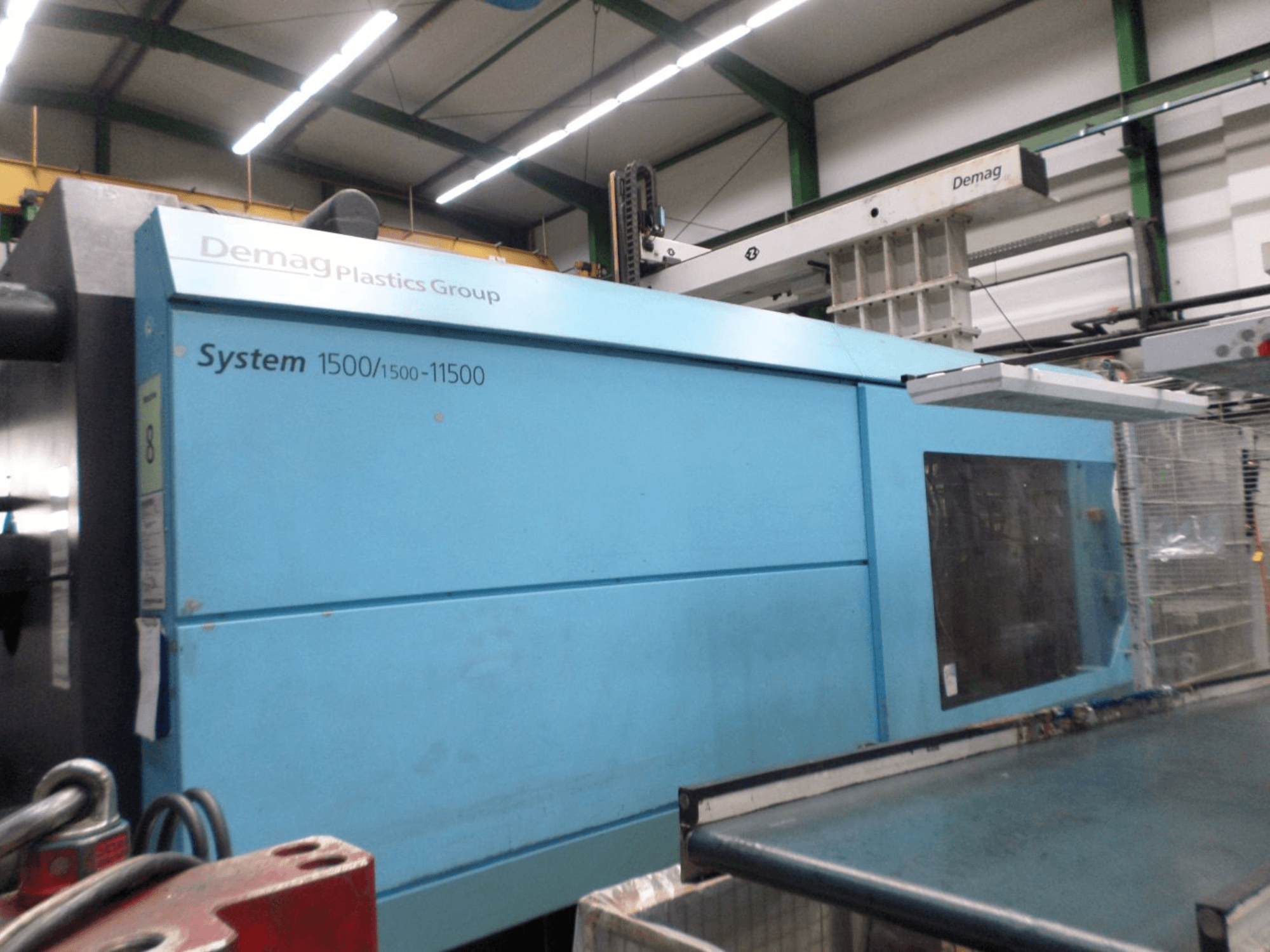 Presse à injection hydraulique Demag D 650 de couleur bleue, vue de profil montrant l'étiquette « System 1500/1500-11500 » et la zone de commande.