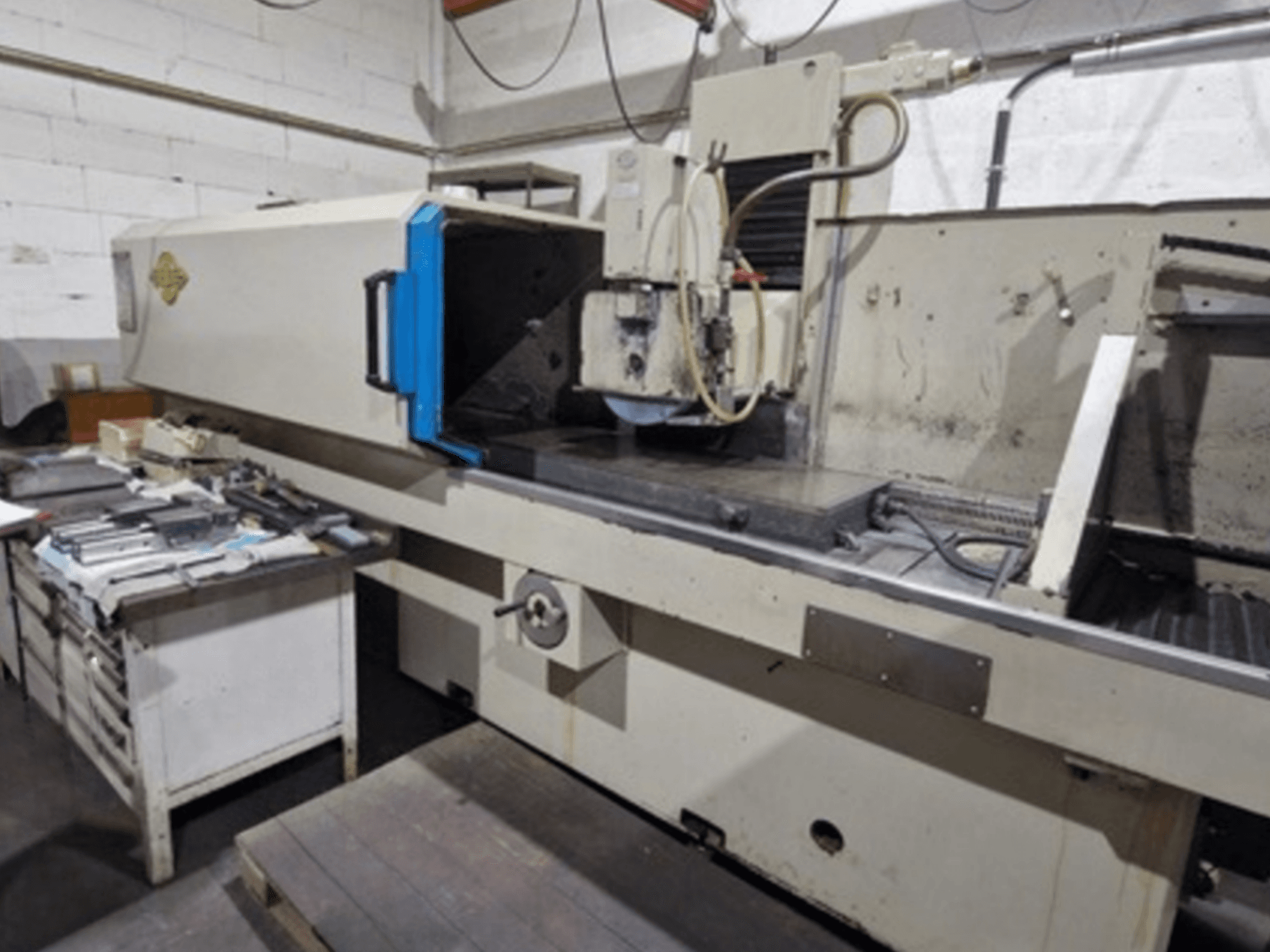 Meuleuse de surface ELB dans un atelier ; vue latérale montrant la table de meulage et les commandes, avec des outils à proximité.