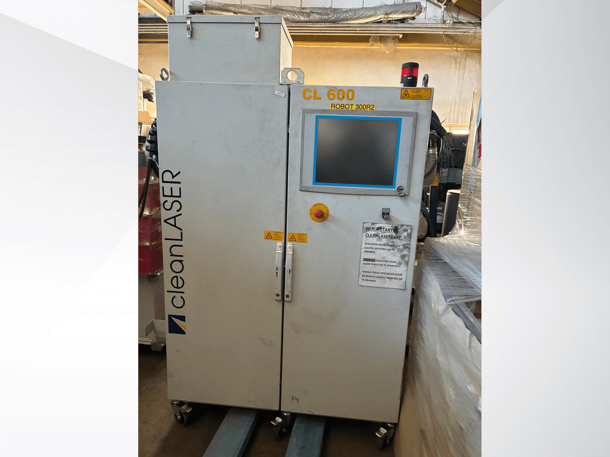 Système d'automatisation CLEAN LASER CL 600, vue de face, avec écran LCD, étiquettes d'avertissement et boutons de commande sur la porte.