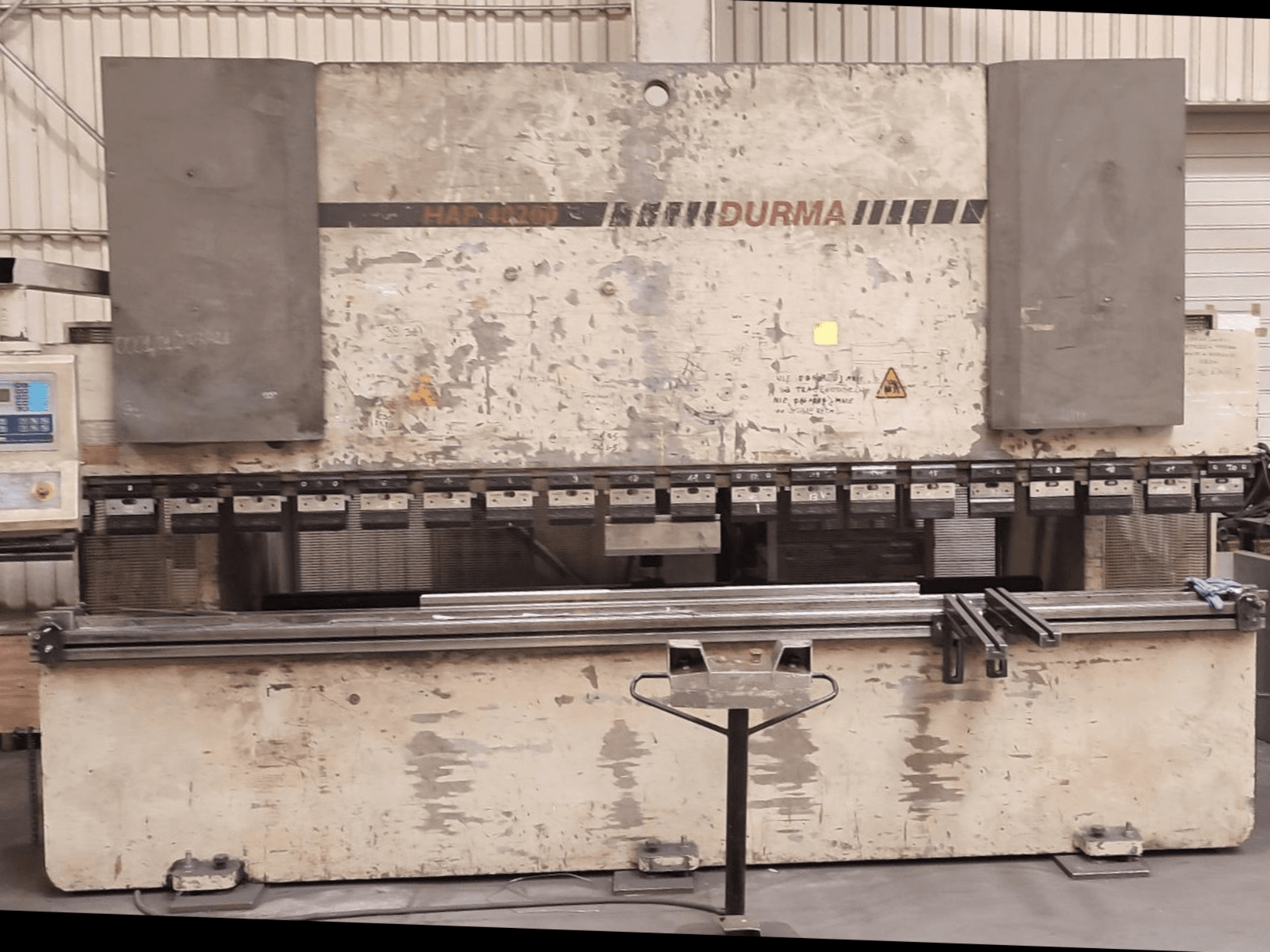 Vue avant de la presse plieuse Durma HAP 40200, avec un extérieur usé, un panneau de commande et des outils de serrage visibles sur la surface de travail.