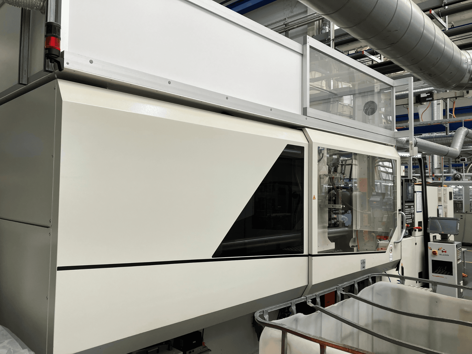 Machine industrielle vue de face, avec un design blanc élégant, un panneau d'affichage et une section en verre pour la visibilité des composants.