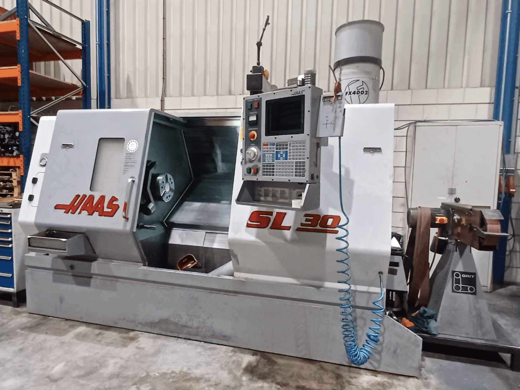 Tour CNC Haas SL 30 en vue latérale, présentant le panneau de commande, la zone d'usinage et le système d'arrosage intégré pour le travail des métaux.