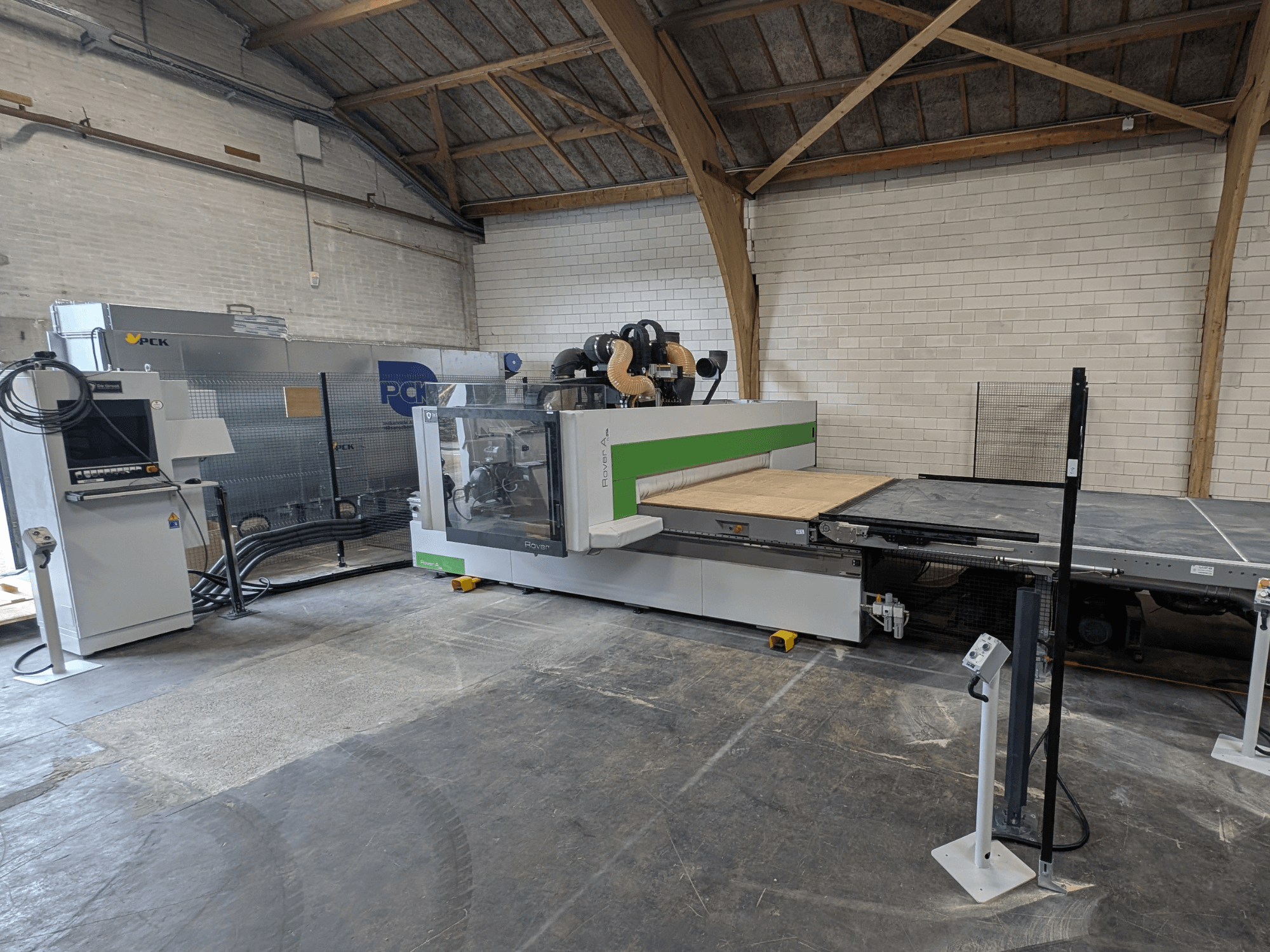 Le centre d'usinage CNC PCK, vue de face, est doté d'un grand banc de coupe, d'un panneau de commande, d'un système d'extraction des poussières et d'une conception robuste.