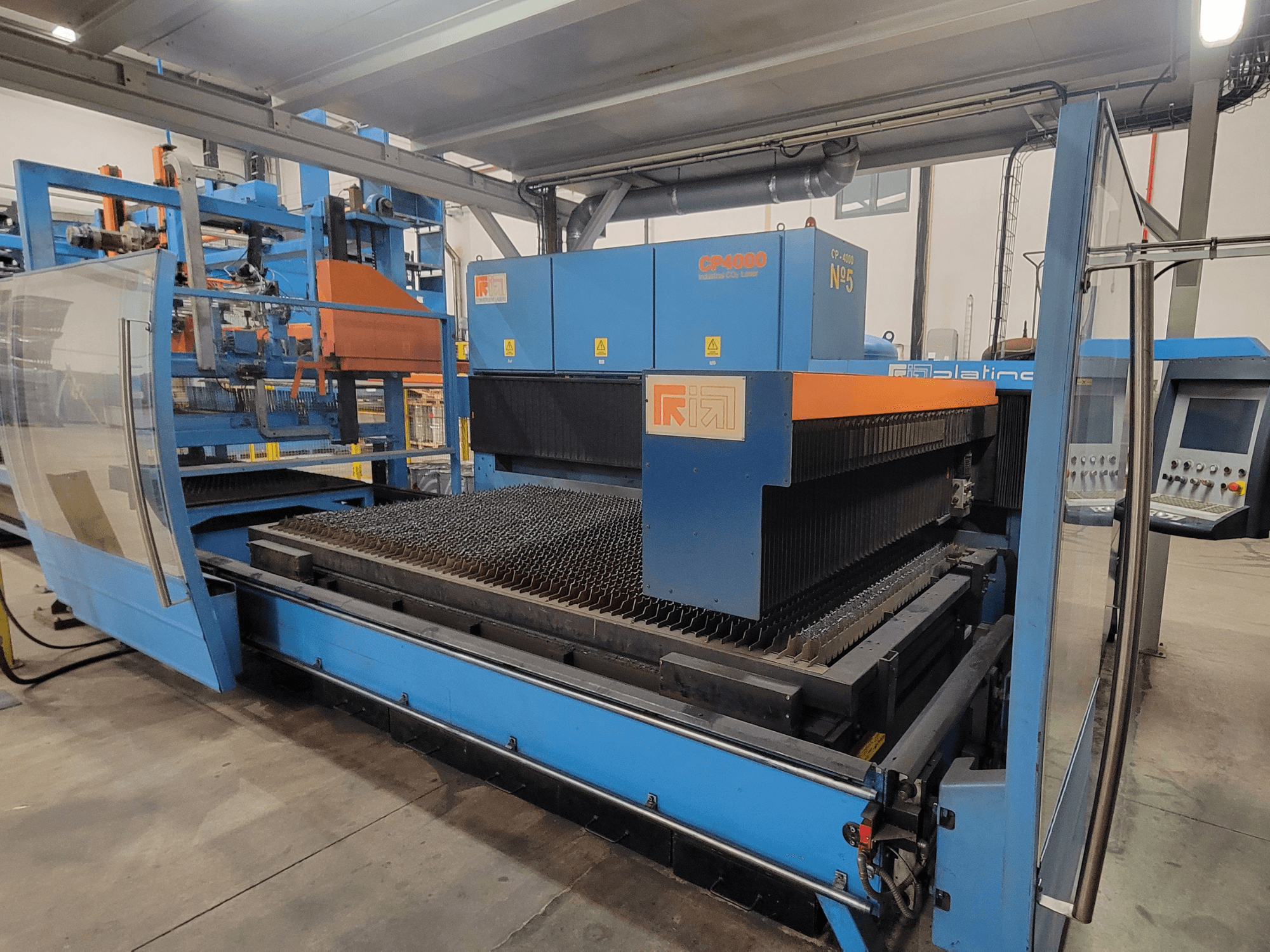 Machine de découpe laser RIK CP4060 en bleu, vue latérale montrant la grille de découpe des métaux et le panneau de commande. Idéale pour les applications industrielles.