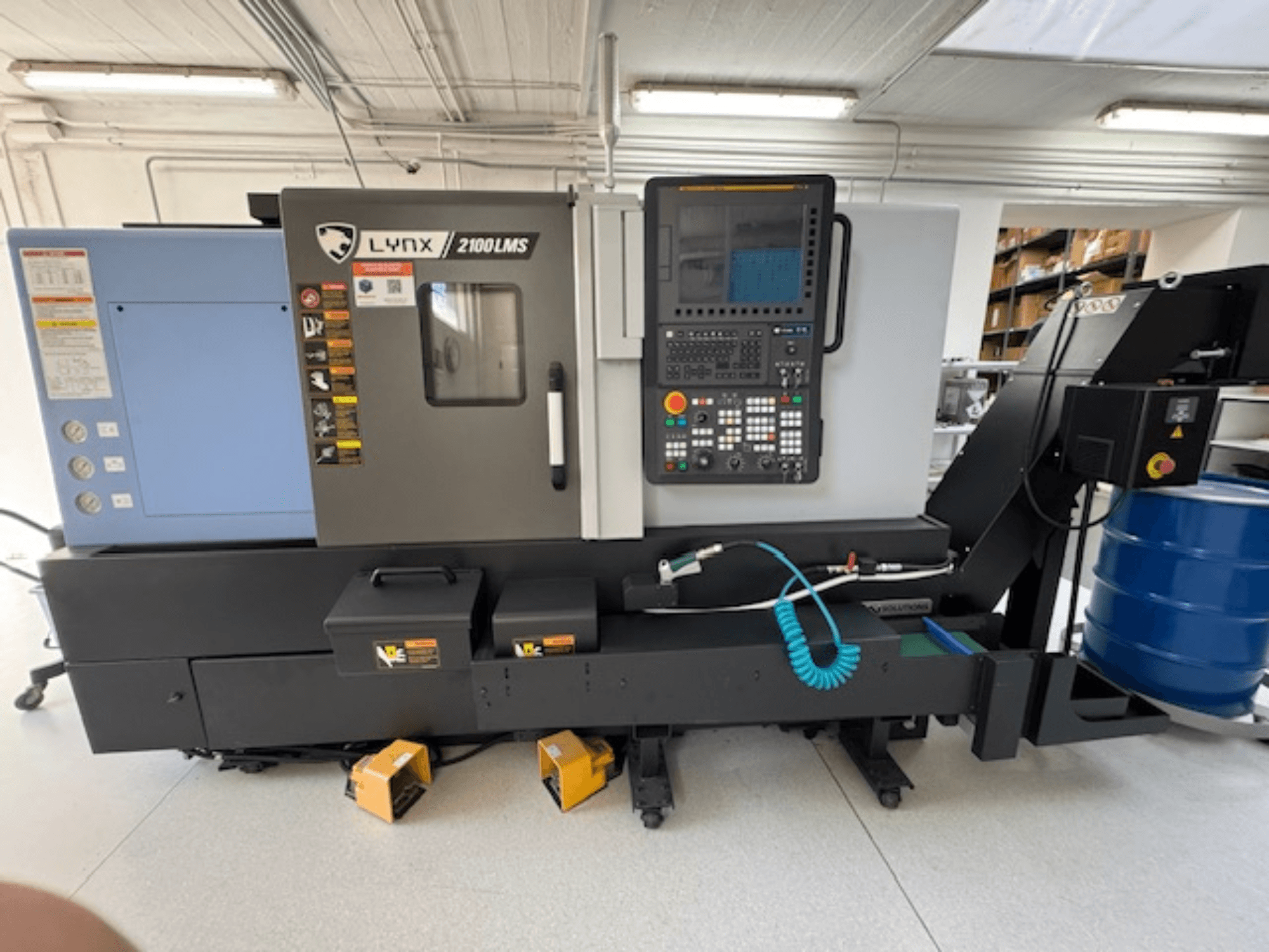 Tour horizontal DOOSAN LYNX 2100LMSA, vue de face, avec panneau de commande, tuyau d'arrosage et boîtes de rangement.