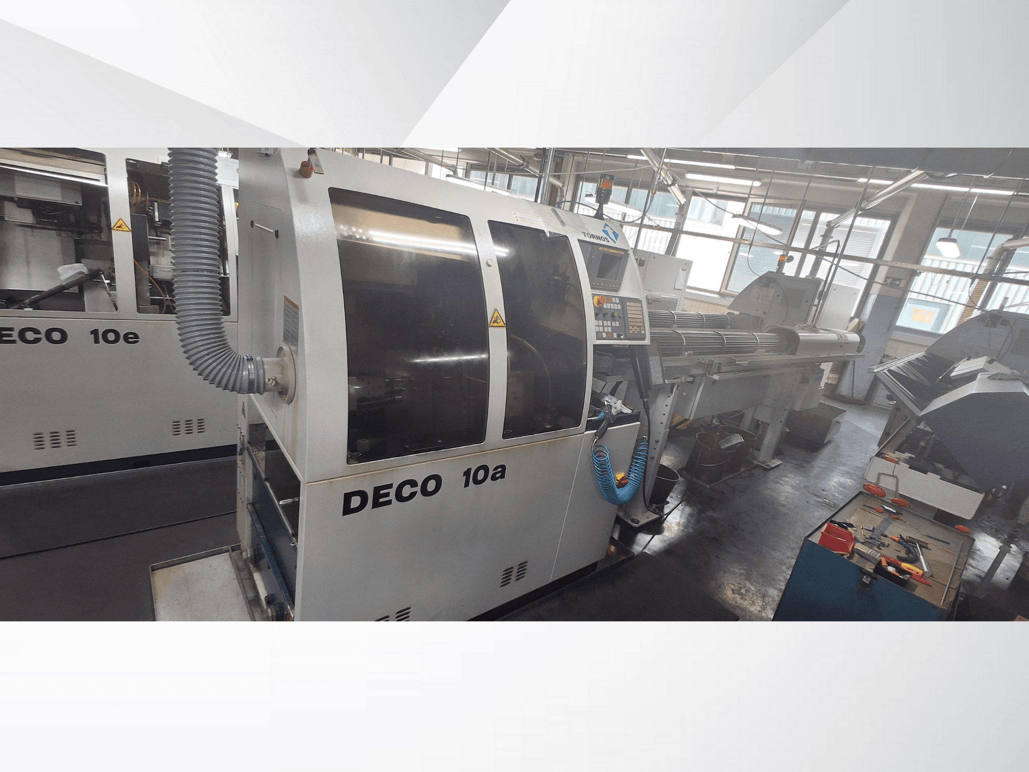 Machine CNC DECO 10a dans un atelier, montrant la vue de face, le panneau de commande et le système d'échappement. Construction robuste et outils de précision.