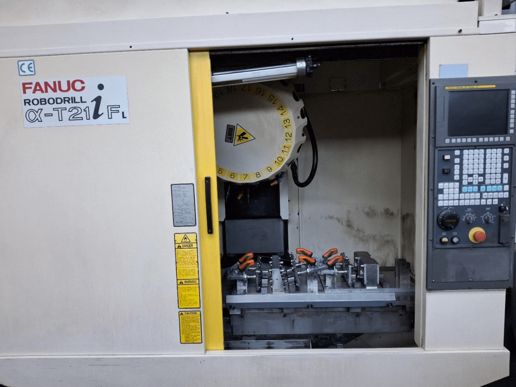 Centre d'usinage vertical FANUC ROBODRILL α-T21iFL vue de face, montrant les outils et les commandes à l'intérieur de l'armoire de la machine.