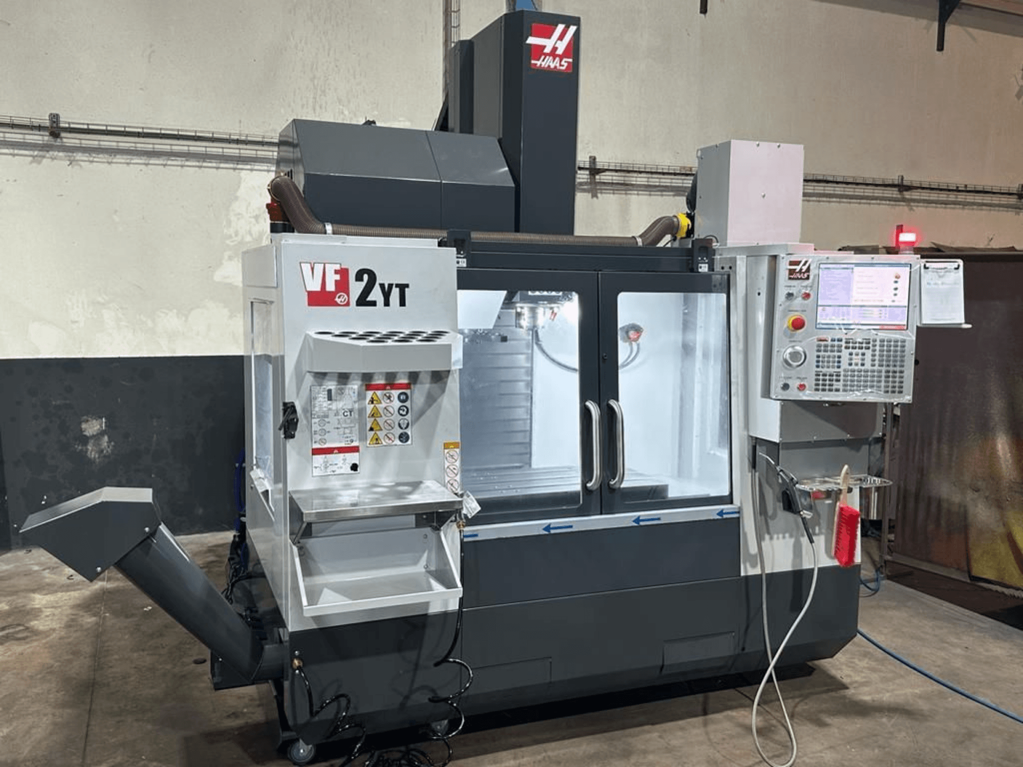 Centre d'usinage vertical HAAS VF-2YT-EU vu de face, mettant en évidence le panneau de commande et le compartiment de rangement des outils.