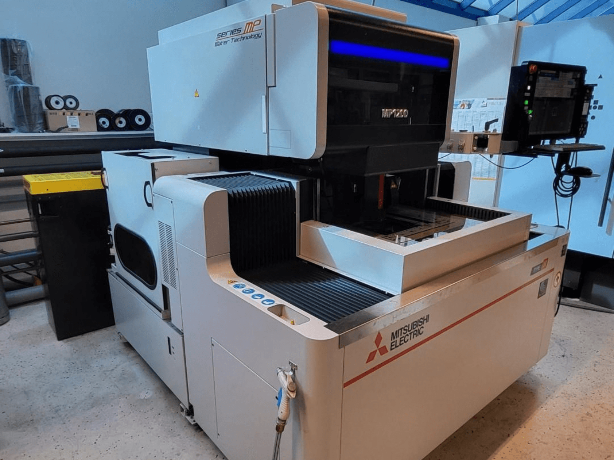 Machine d'électroérosion à fil Mitsubishi MP1200, vue de face, mettant en avant le panneau de commande, ses détails high-tech et son design épuré.