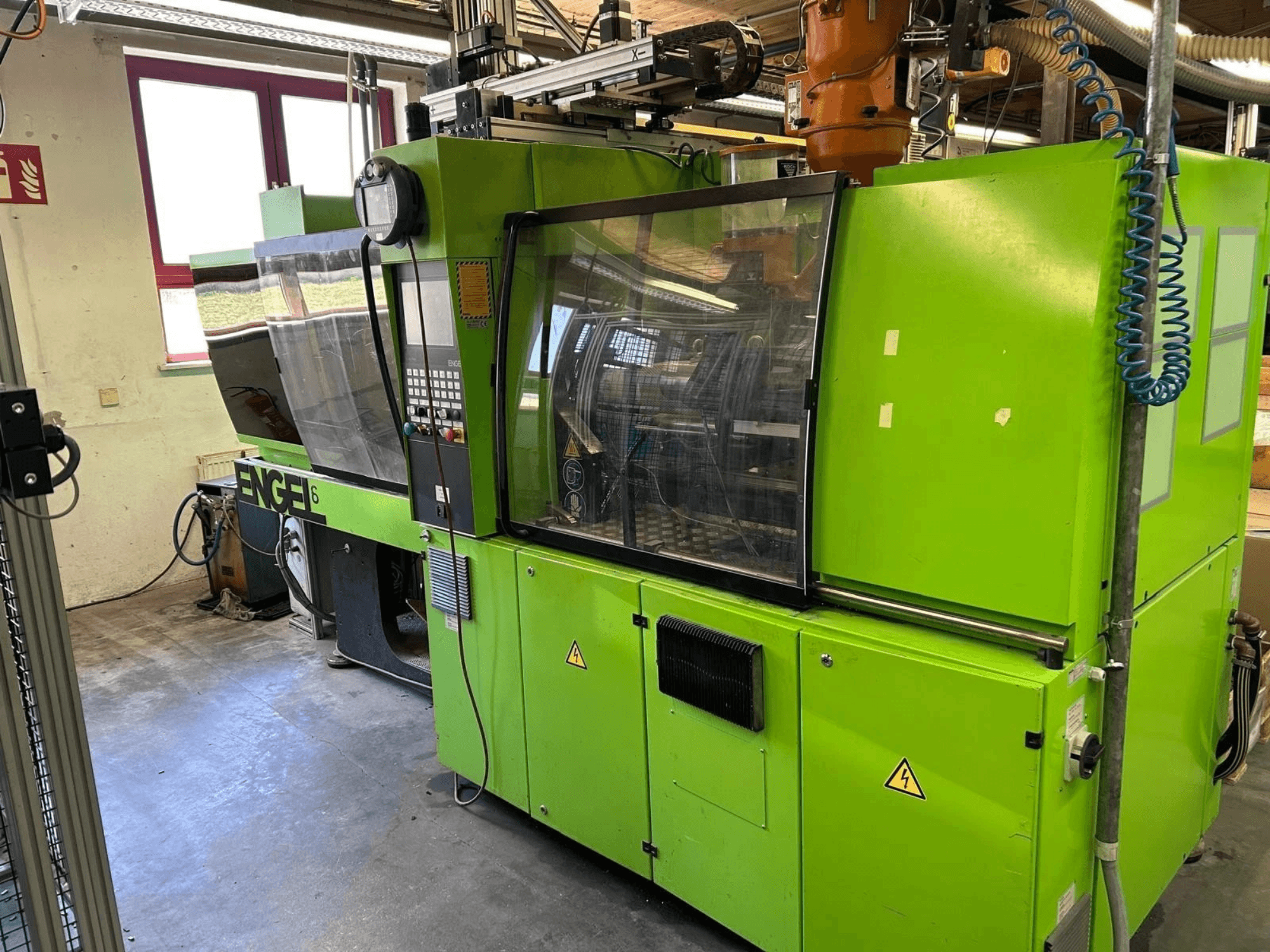 Vue de face de la presse à injection hydraulique Engel VICTORY 330/80 Tech, mettant en avant sa carrosserie verte et son panneau de commande.