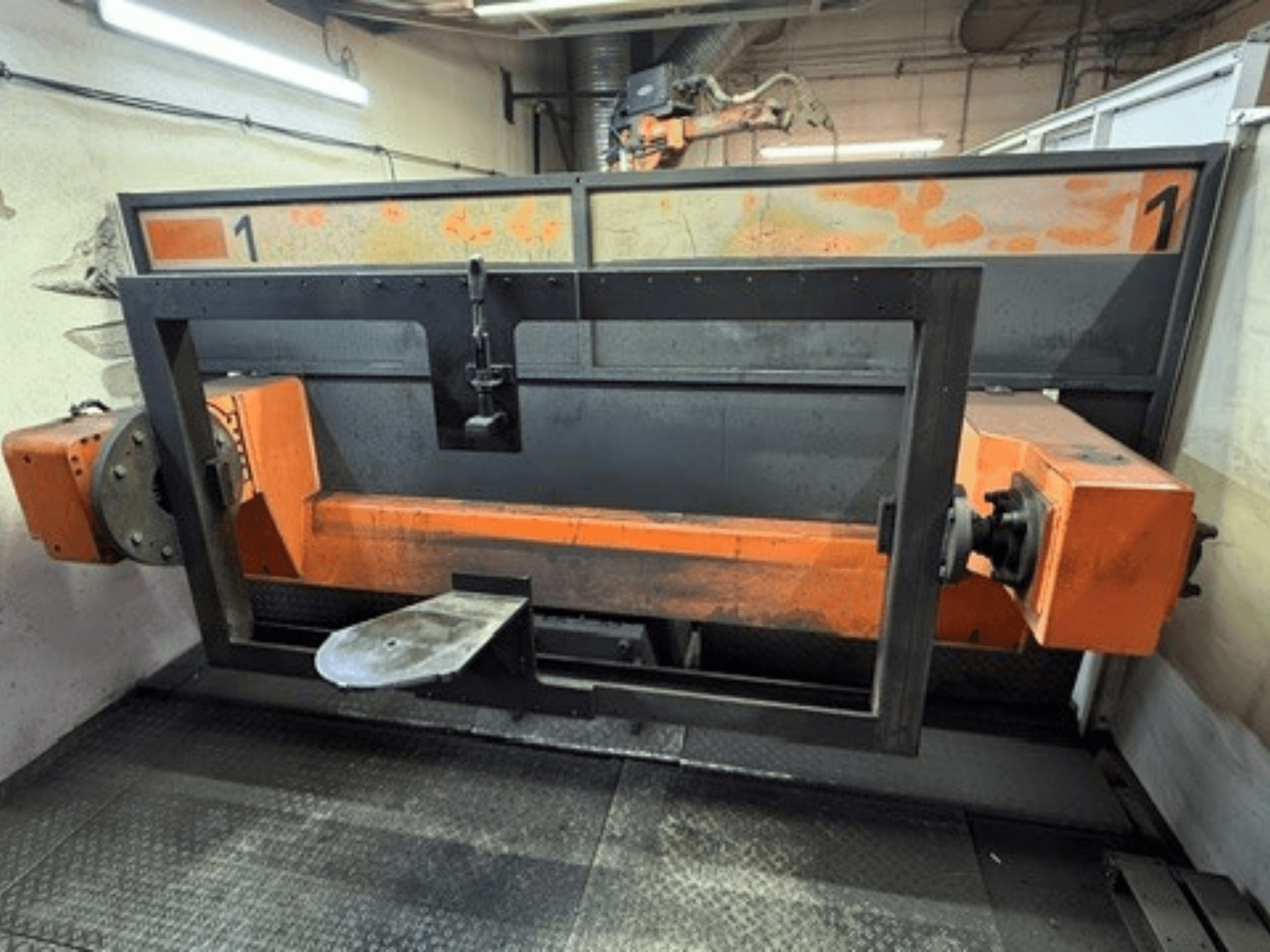 Vue de face de la cellule de soudage ABB IRB 2400L, montrant un grand châssis robotisé composé d'éléments orange et noirs, dans un atelier.