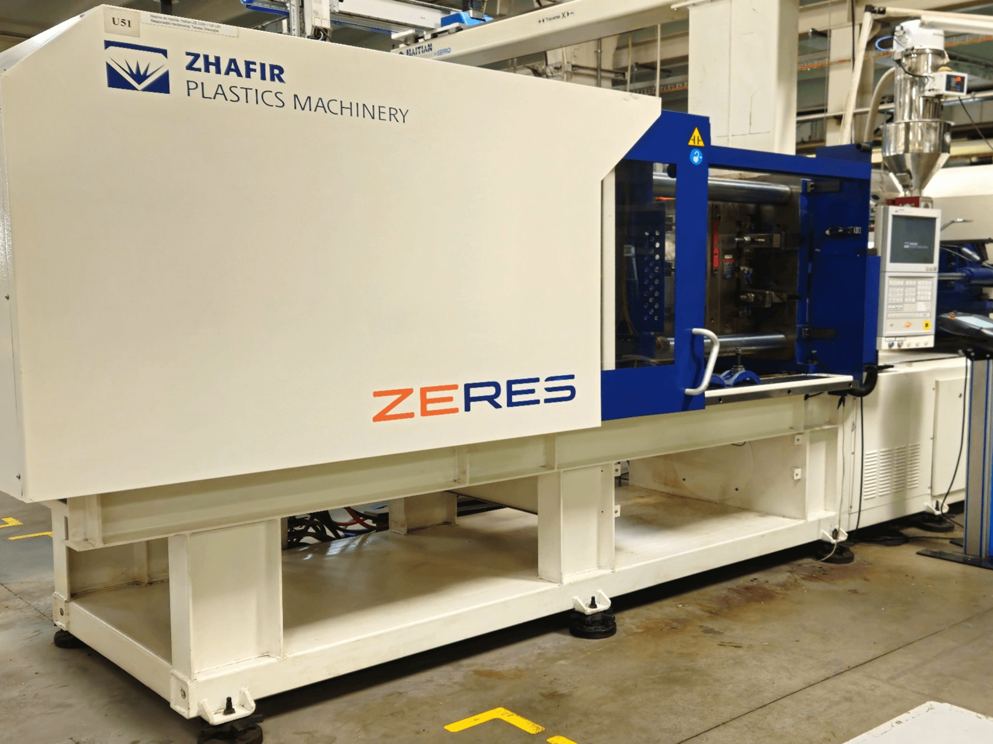 Machine de moulage par injection de plastique Zhafir Zeres, vue de côté, montrant le panneau de commande, la trémie et le design épuré blanc/bleu.