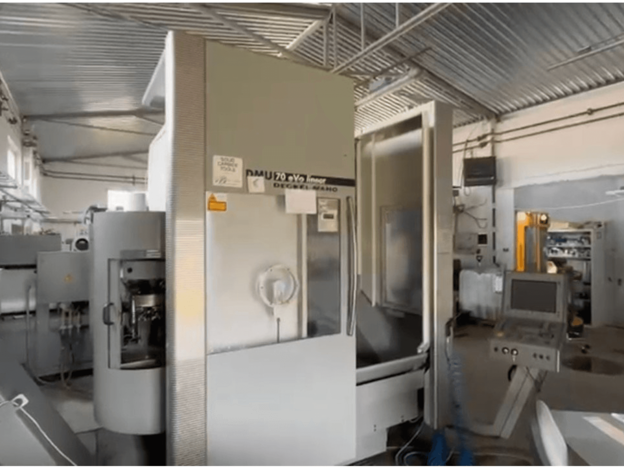 Machine CNC linéaire DMU 70 eVo dans un atelier, vue de face, dotée d'un panneau de commande et d'un design moderne.