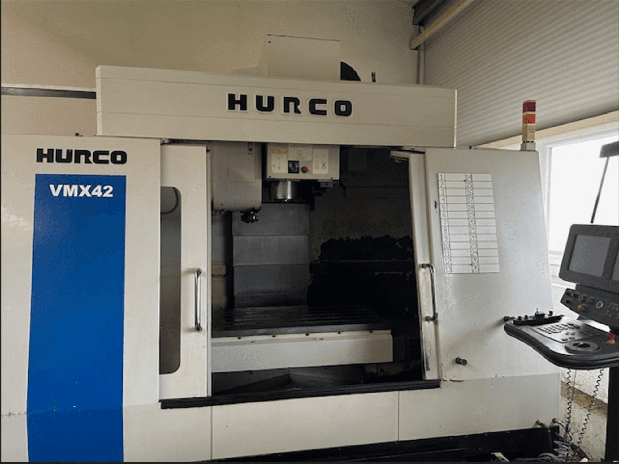 Fraiseuse CNC Hurco VMX42, vue de face, dotée d'un panneau de commande et d'un espace de travail ouvert pour les opérations d'usinage.