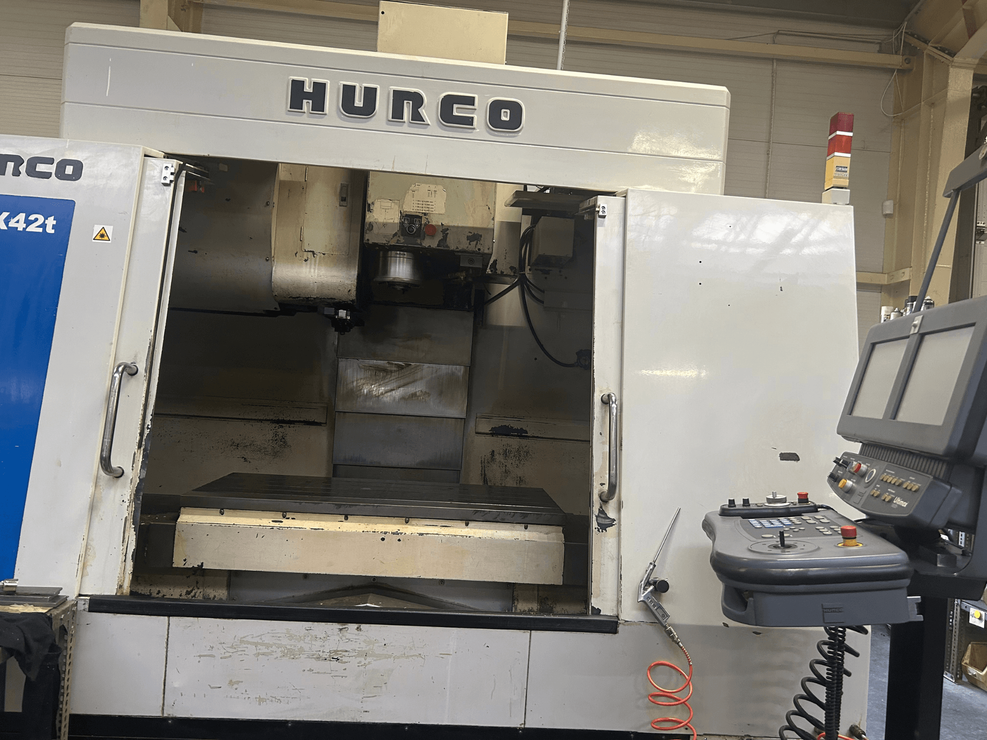 Fraiseuse CNC Hurco VMX42T vue de face, avec un espace de travail ouvert et un panneau de commande avec boutons et écran.