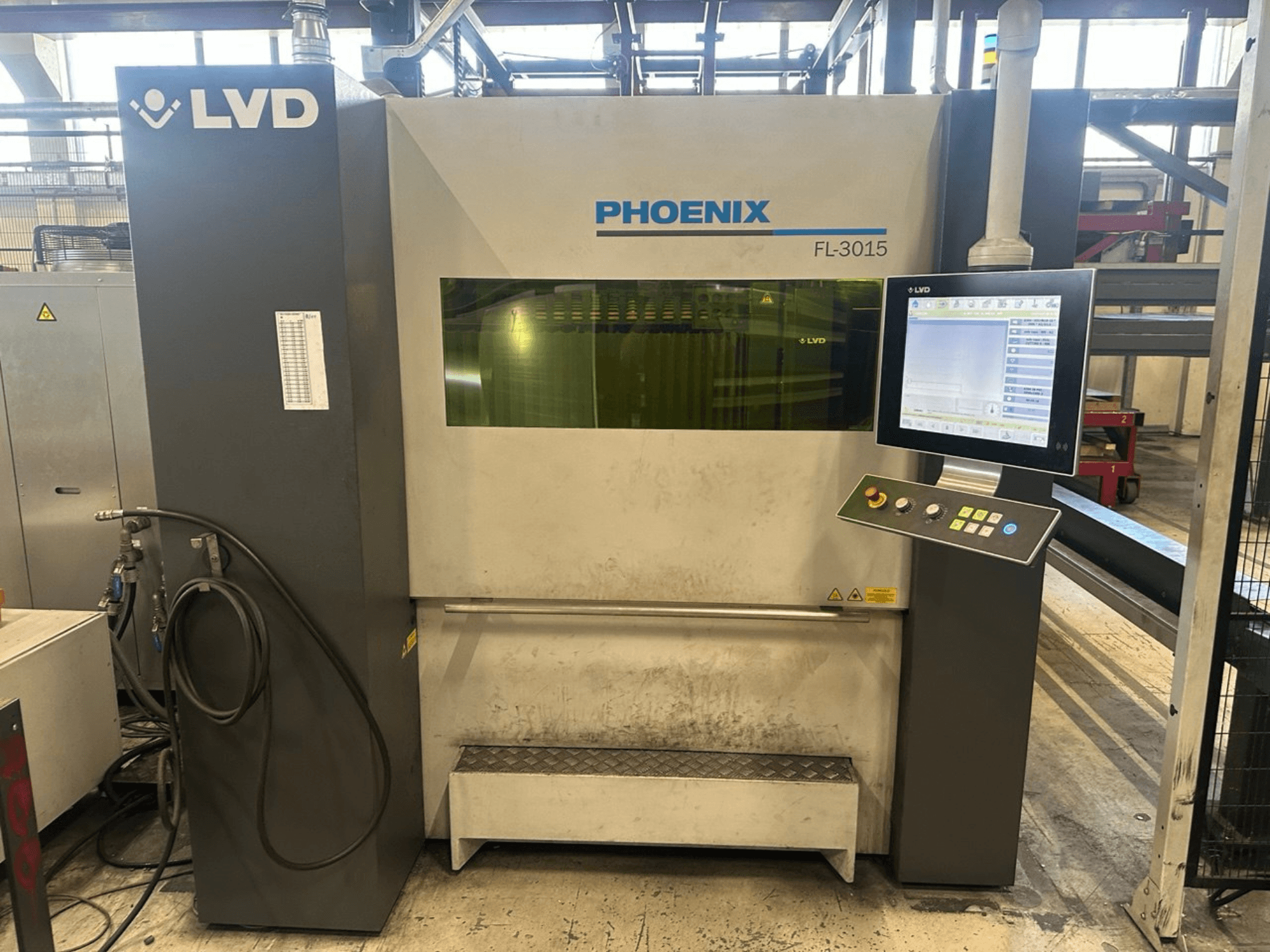 La machine de découpe laser LVD Phoenix FL-3015, vue de face, est équipée d'un panneau de commande numérique et de tubes visibles.