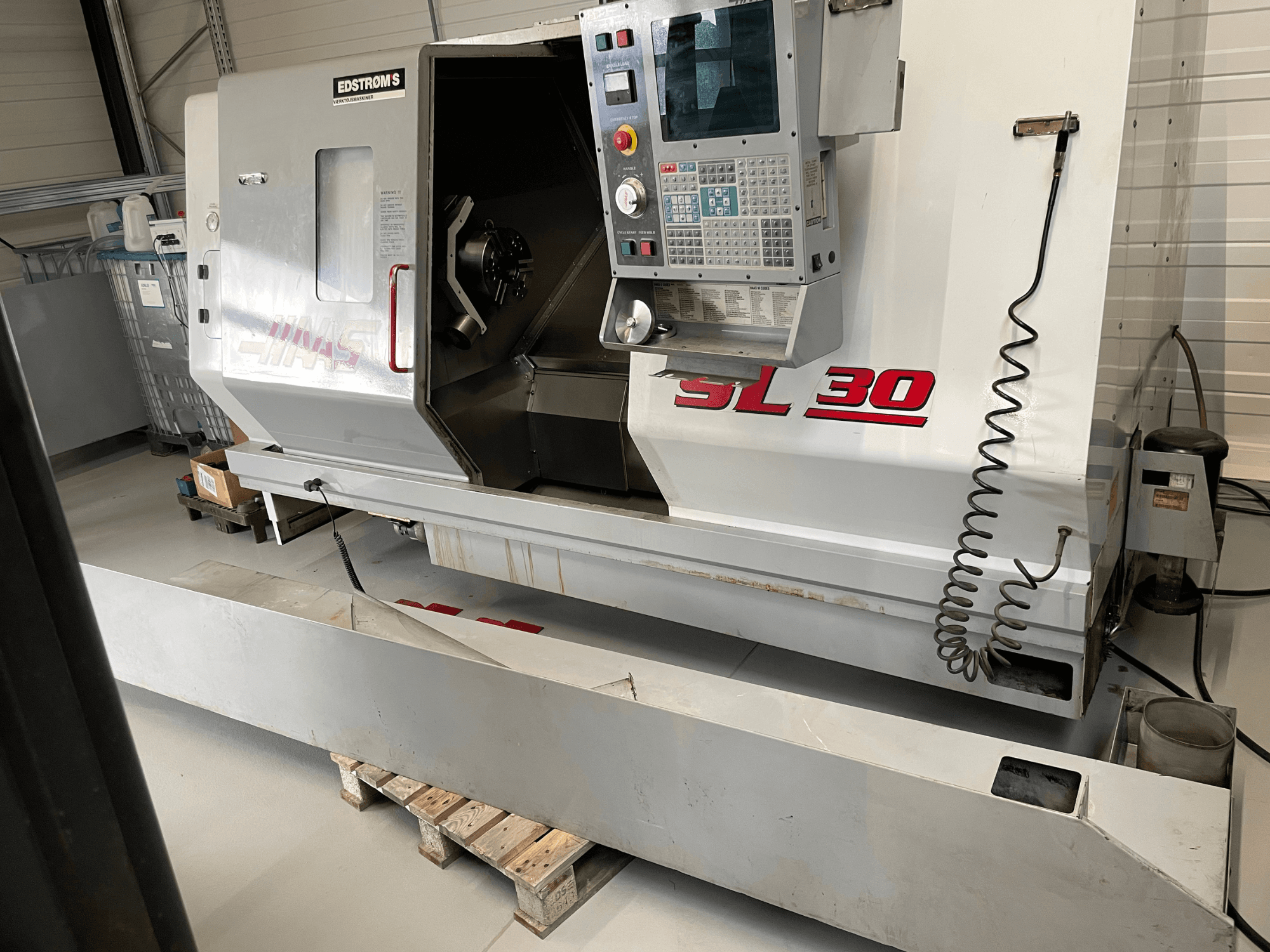 Tour CNC Haas SL 30 dans un atelier, vue latérale, avec panneau de commande et broche ouverte pour les tâches d'usinage.