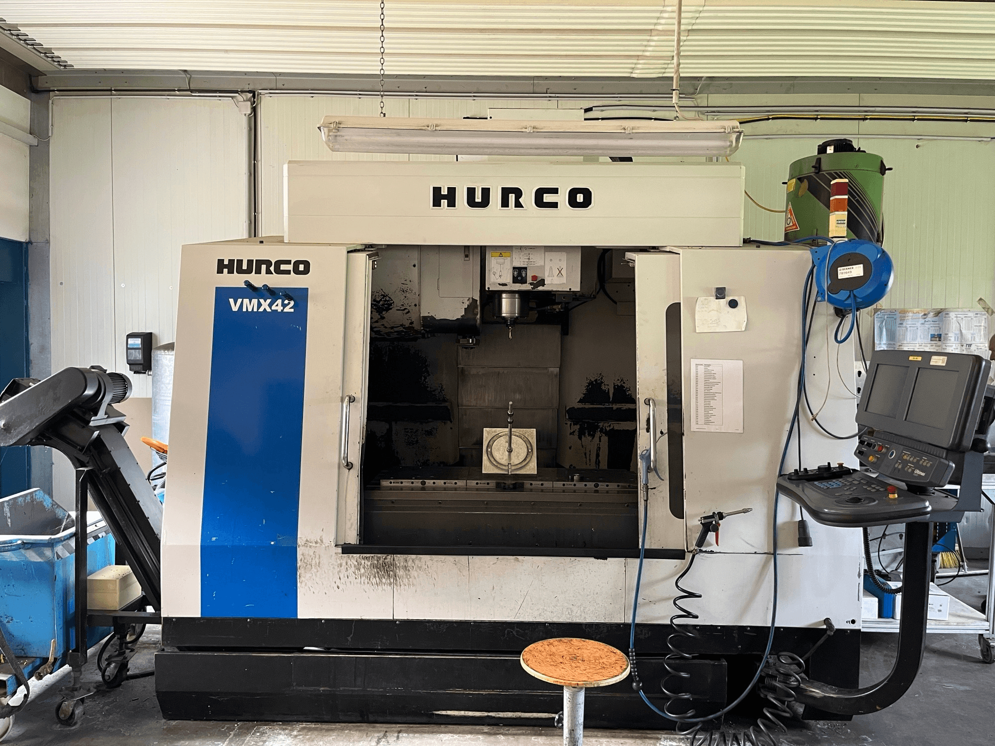 Centre d'usinage vertical Hurco VMX 42 en vue latérale, montrant le panneau de commande, la broche et la configuration de la pièce à usiner.