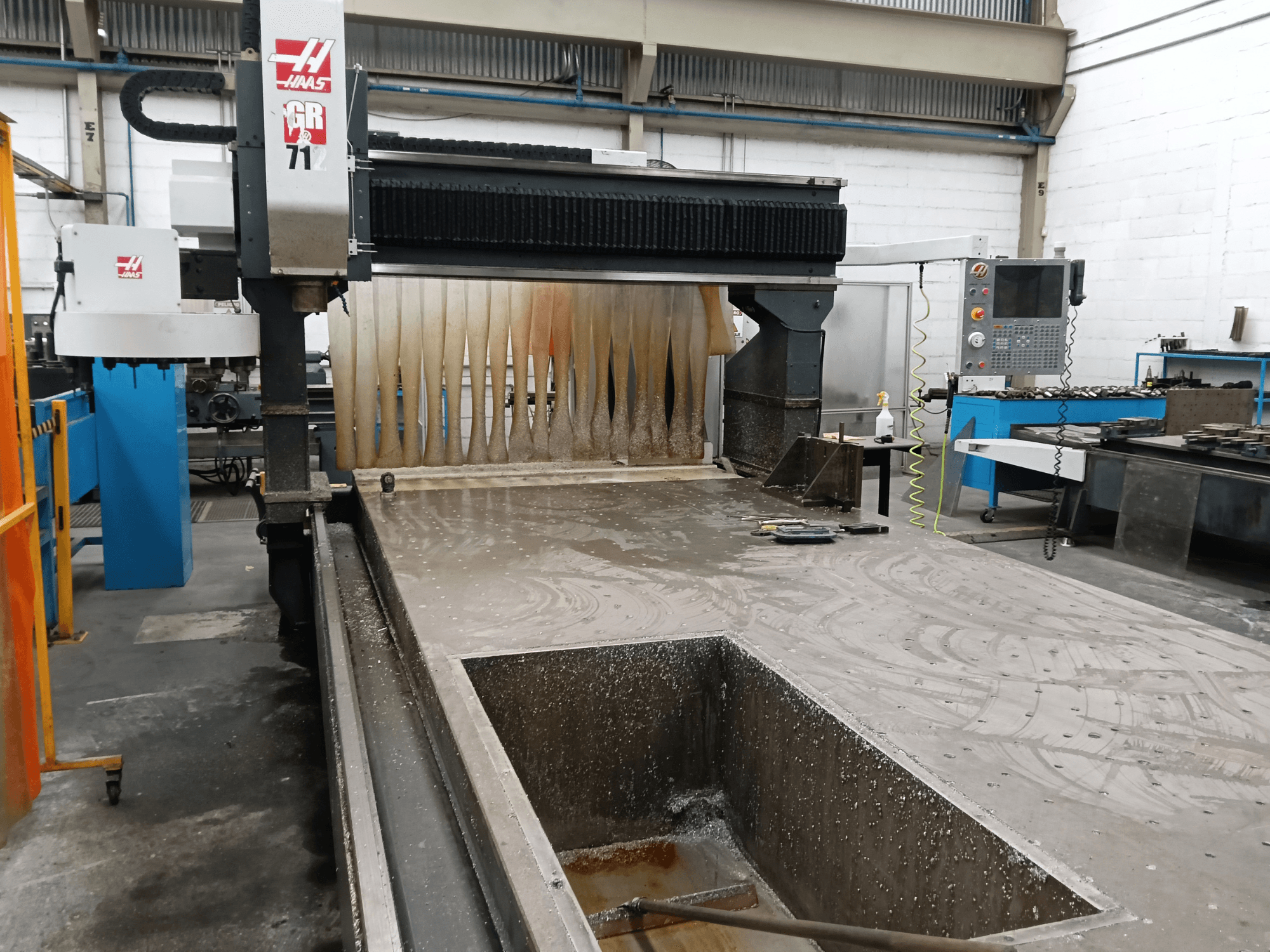 Fraiseuse à portique HAAS GR-712 vue de face, montrant une surface de coupe humide et le panneau de commande de l'opérateur.