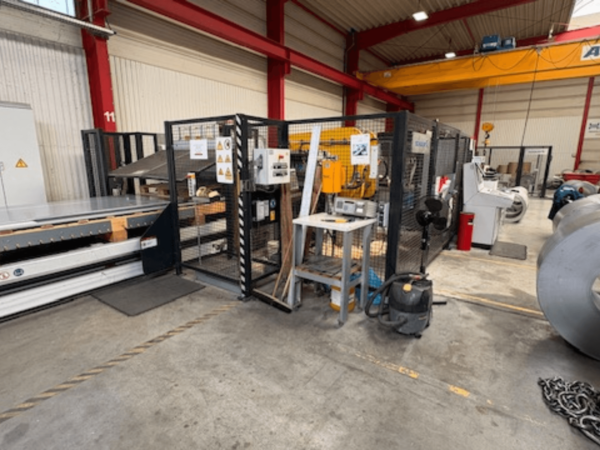 Machine pour la transformation de la tôle de marque SCHULER, modèle AC-PLS-1600-M, dans un atelier ; vue de profil montrant le capot de sécurité et les équipements adjacents.