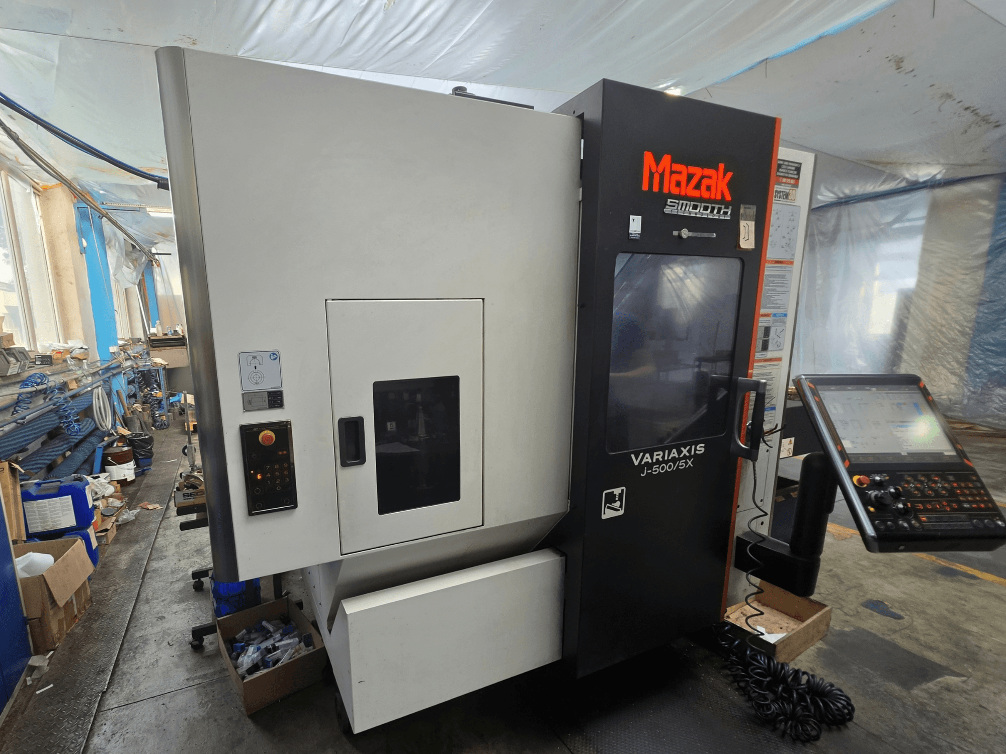 Centre d'usinage vertical Mazak VARIAXIS J-500/5X, vue de profil montrant les commandes et l'écran, installé dans un atelier.