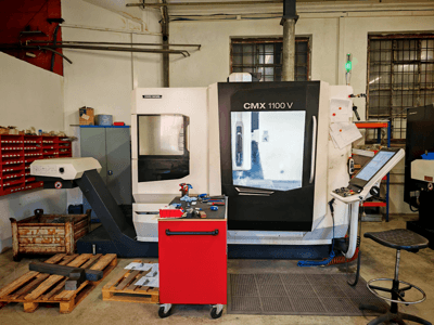 Centre d'usinage vertical DMG MORI CMX 1100 V dans l'atelier, vue de face, montrant le panneau de commande et les outils environnants.