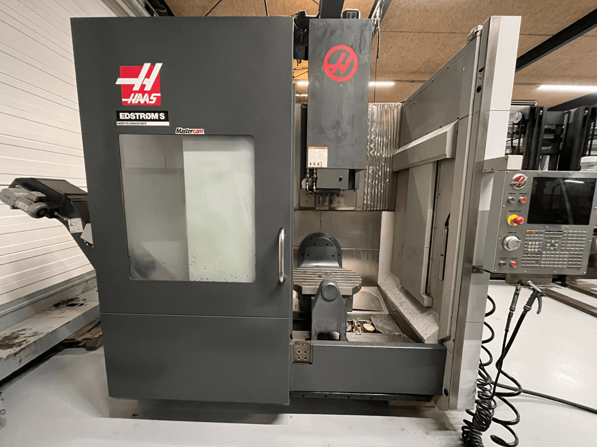 Vue avant de la machine CNC Haas EDSTROM S montrant le panneau de commande, la tête de broche et la table d'usinage.