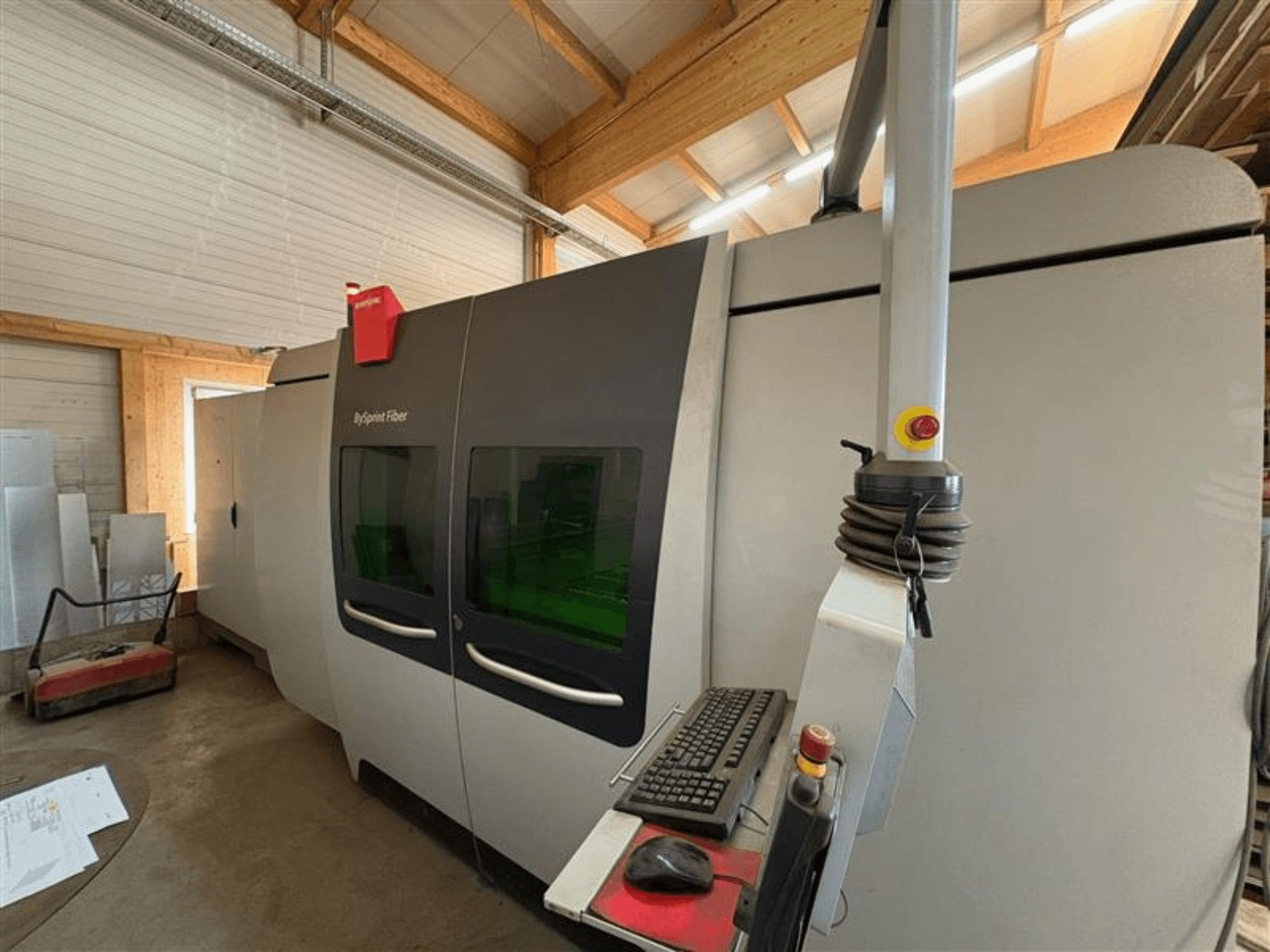 Machine de découpe Bystronic ByJet Fiber dans un atelier, vue de face montrant le panneau de commande et les deux fenêtres de visualisation vertes.