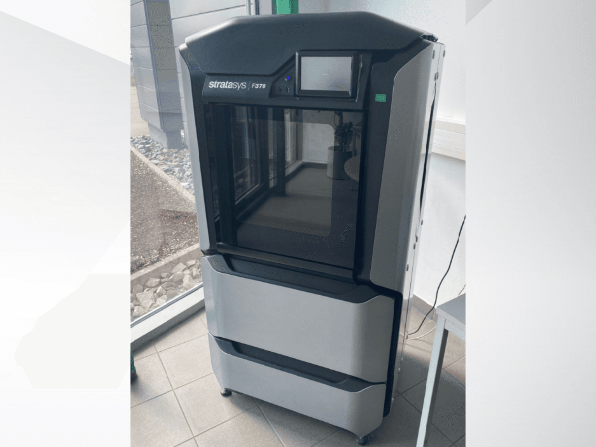 Imprimante 3D en plastique Stratasys F370, vue de face, présentant un design noir et gris élégant avec un écran tactile.