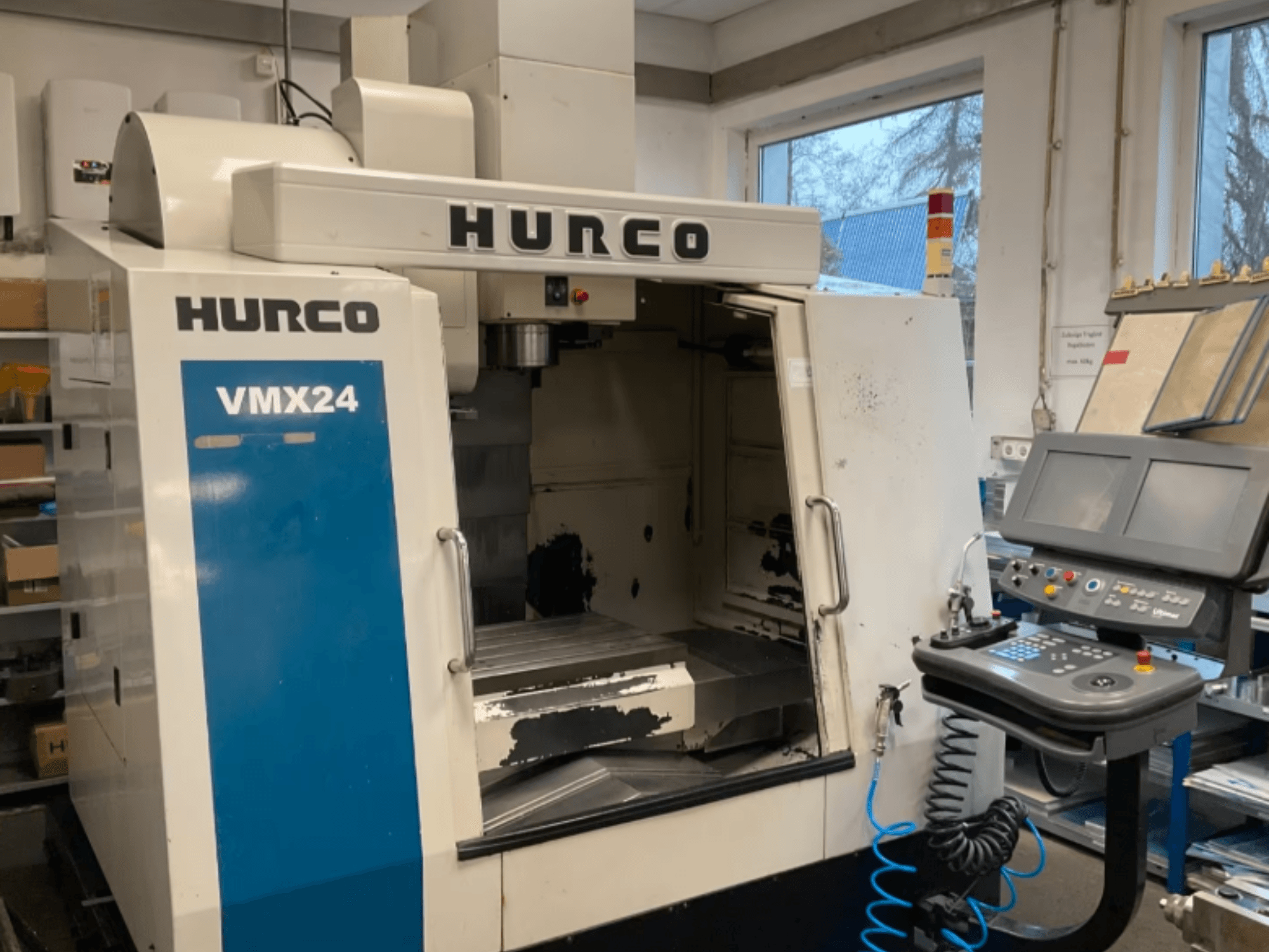 Vue de face du centre d'usinage vertical Hurco VMX24, montrant le panneau de commande, la tête de broche et la zone de travail, avec quelques traces d'usure visibles.
