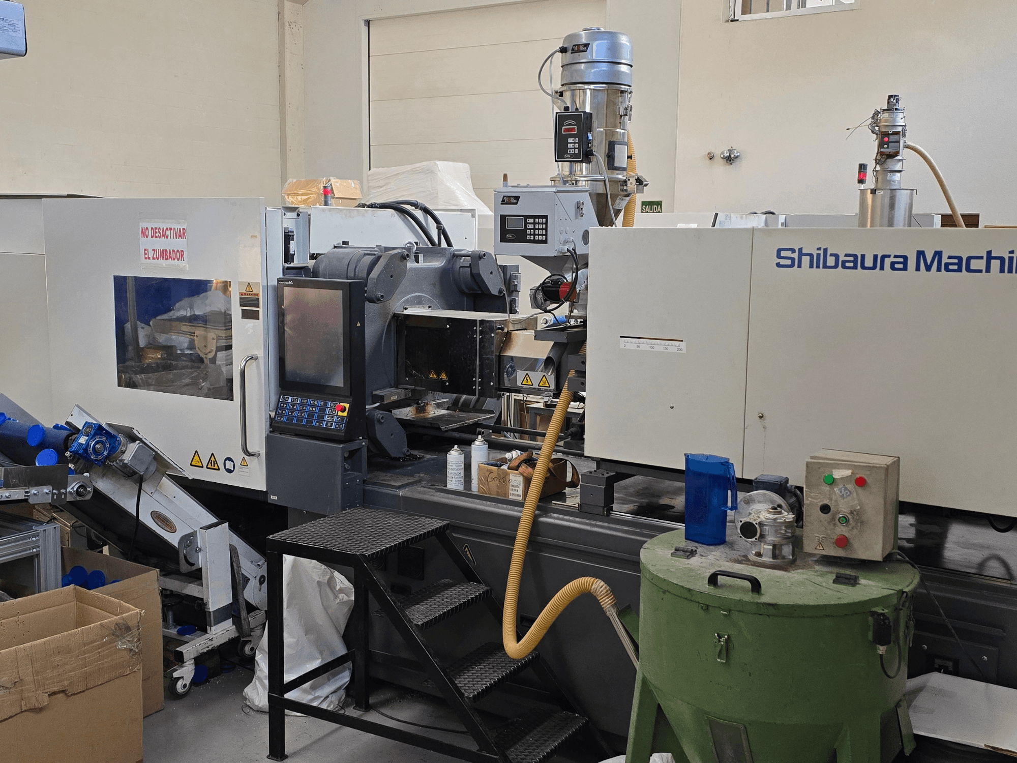 Vue de face de la machine électrique de moulage par injection SHIBAURA EC230SXIII-8A avec le panneau de commande et les équipements adjacents.