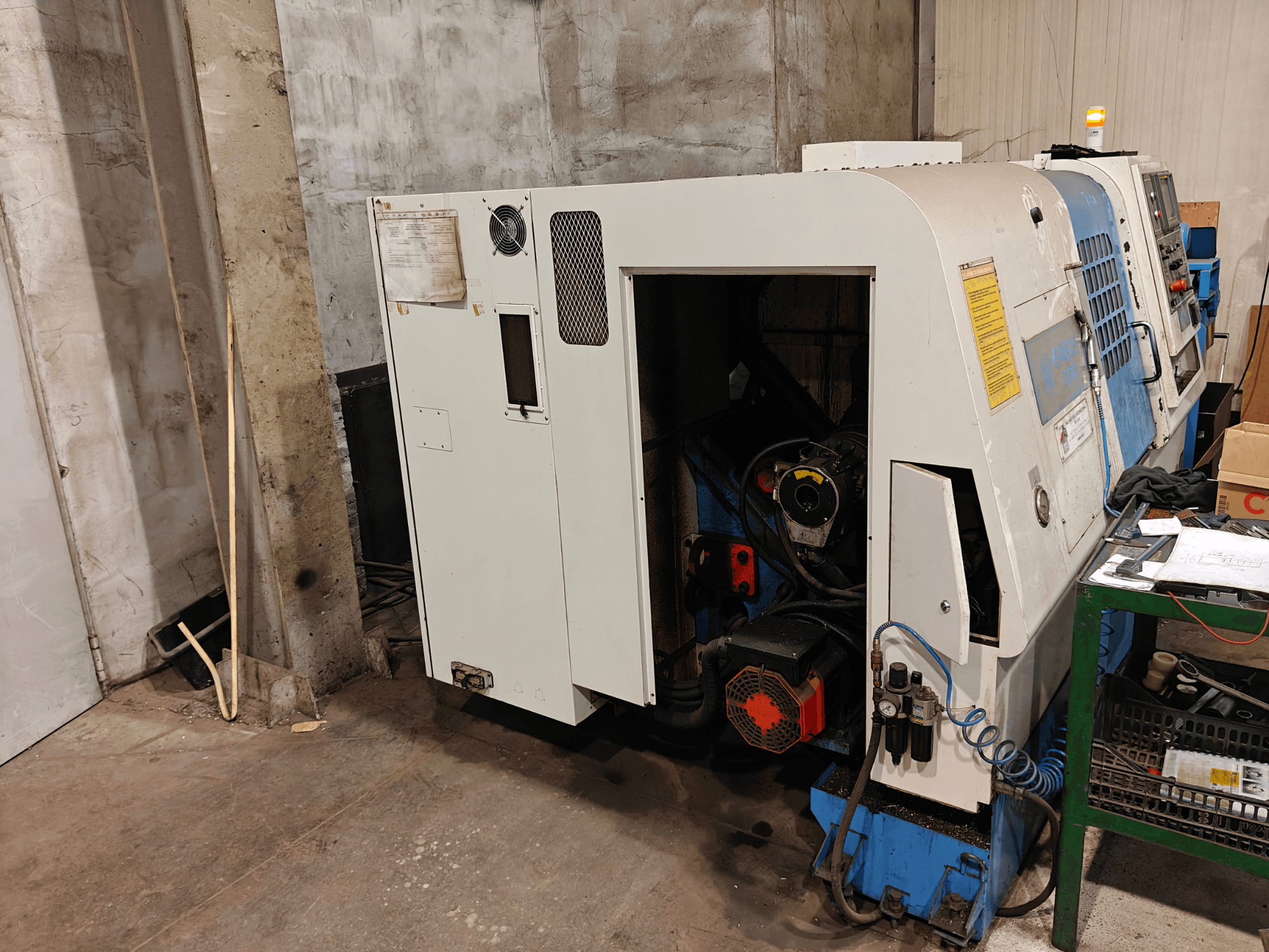 Vue de face d'un tour, dont la marque et le modèle ne sont pas spécifiés, comportant des commandes et des composants de moteur visibles.