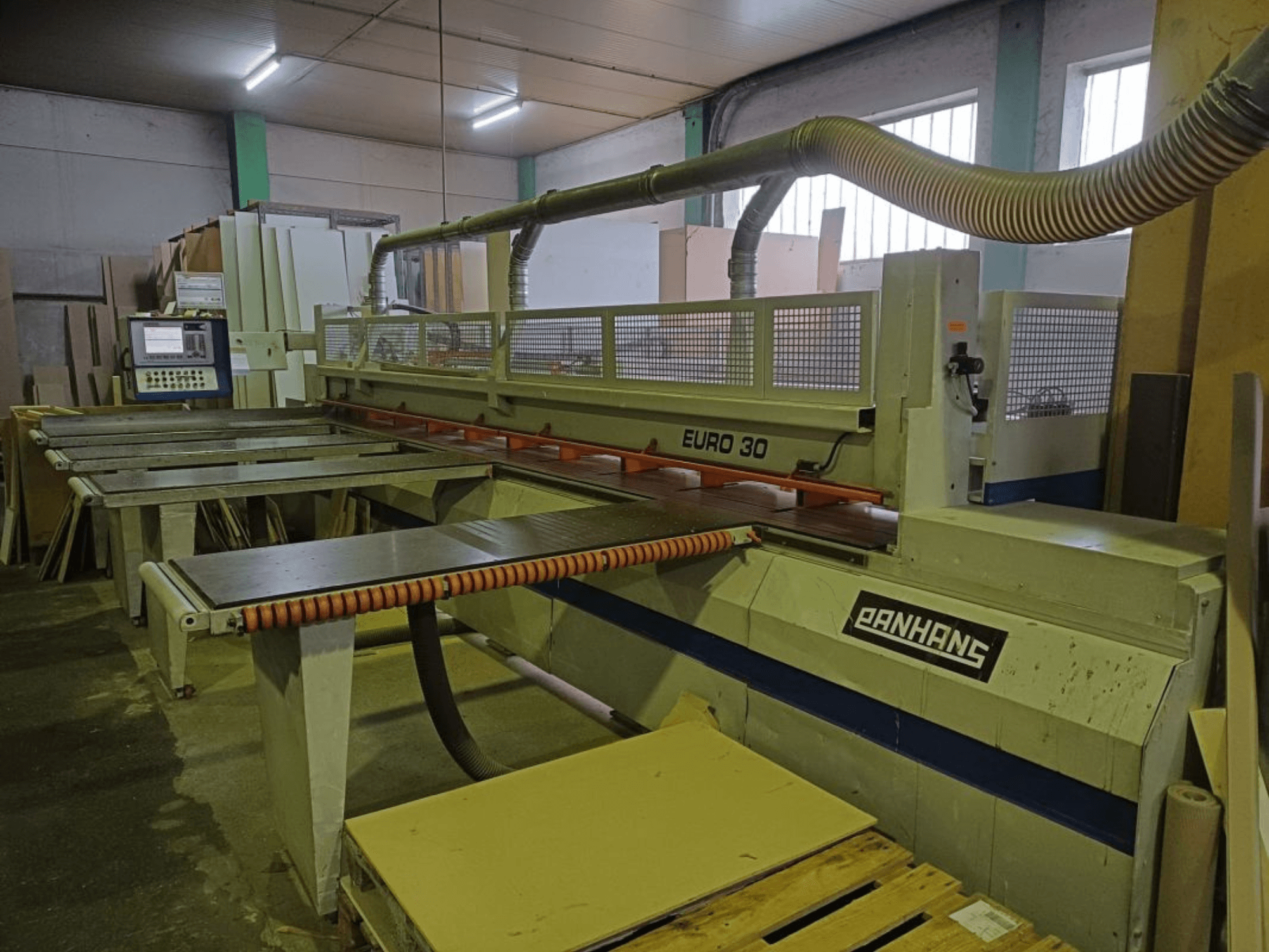 Vue avant de la scie à panneaux PANHANS EURO 30 avec panneau de commande, table de coupe et tuyau d'extraction de la poussière dans un atelier.