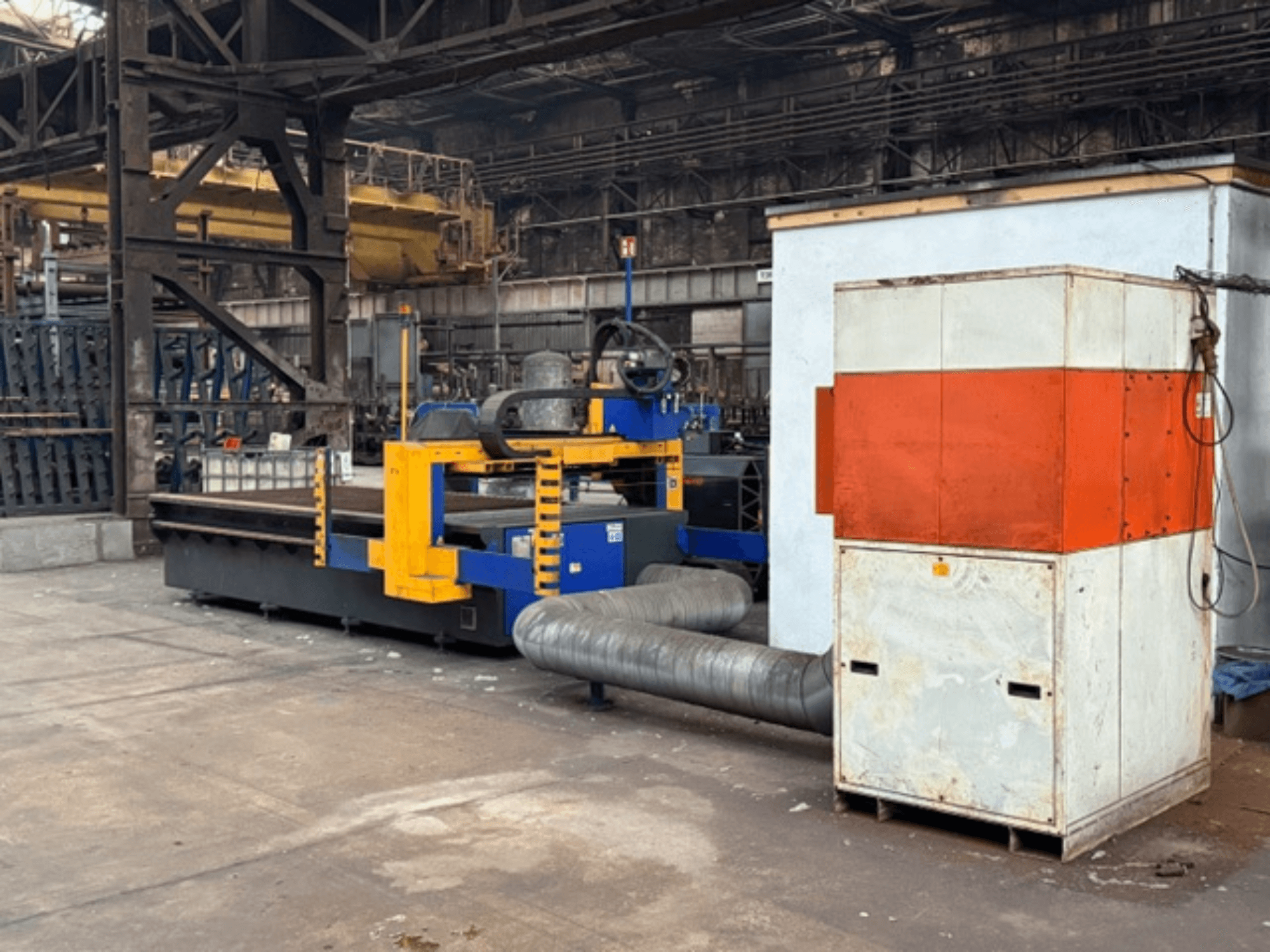 Machine de découpe plasma MicroStep 3001.15P/ME en usine, vue latérale, avec des composants jaunes et bleus et un système d'échappement.