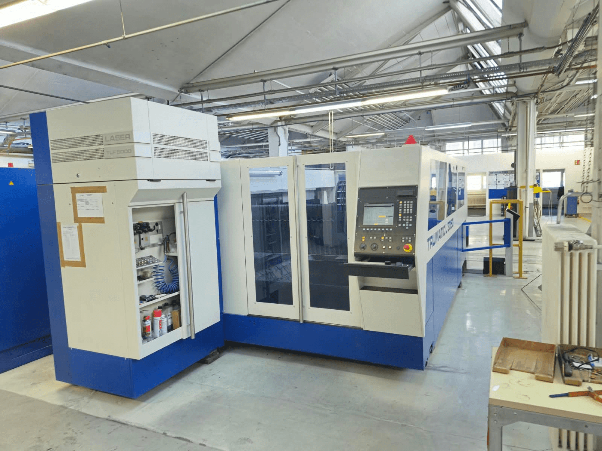 Machine de découpe laser CO₂ TRUMPF TruLaser L3050, vue de face, avec panneau de commande et porte d'accès pour la maintenance, dans son environnement d'usine.