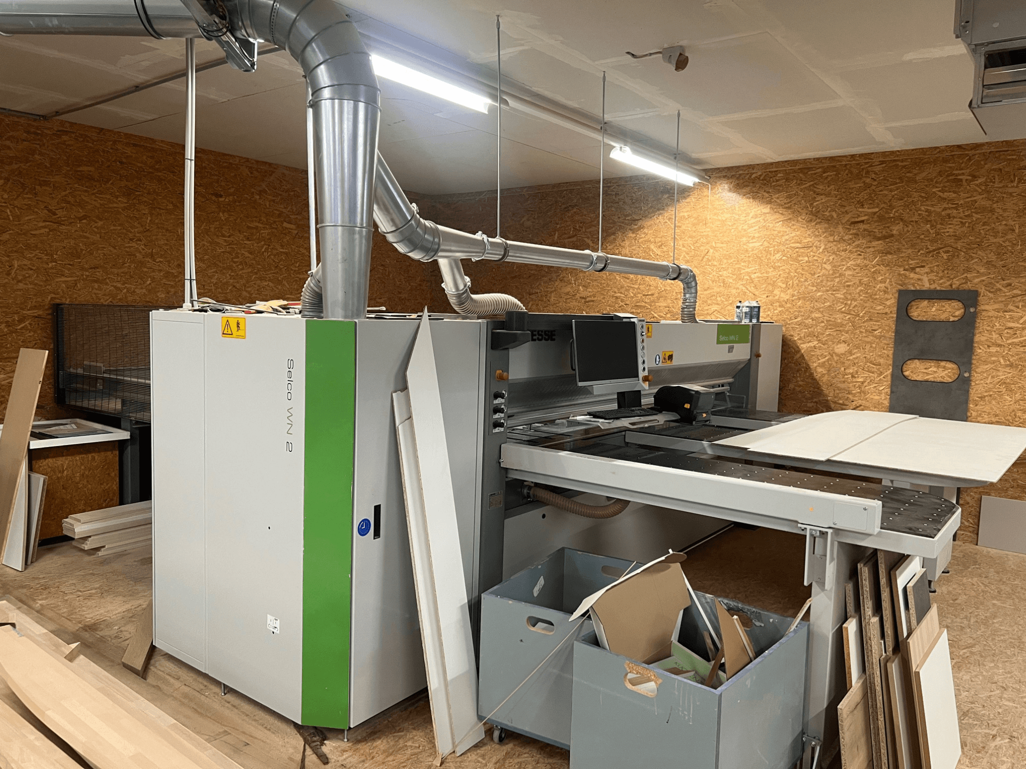 Scie à panneaux BIESSE Selco WN 2 dans un atelier, avec une grande table de coupe et un système d'aspiration des poussières, vue de côté.