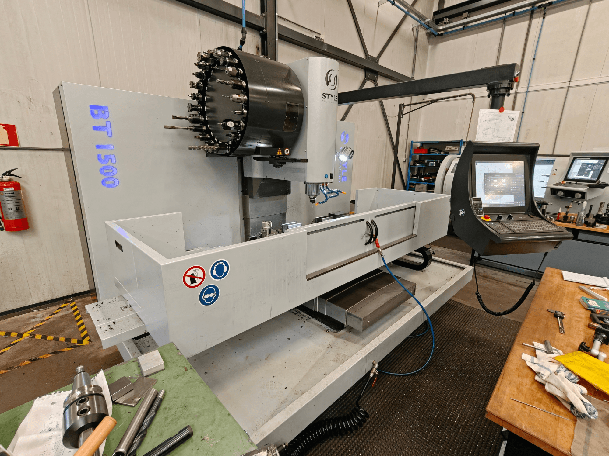 Centre d'usinage vertical STYLE BT 1500 dans un atelier, présentant un panneau de commande, un porte-outil et une zone de travail.