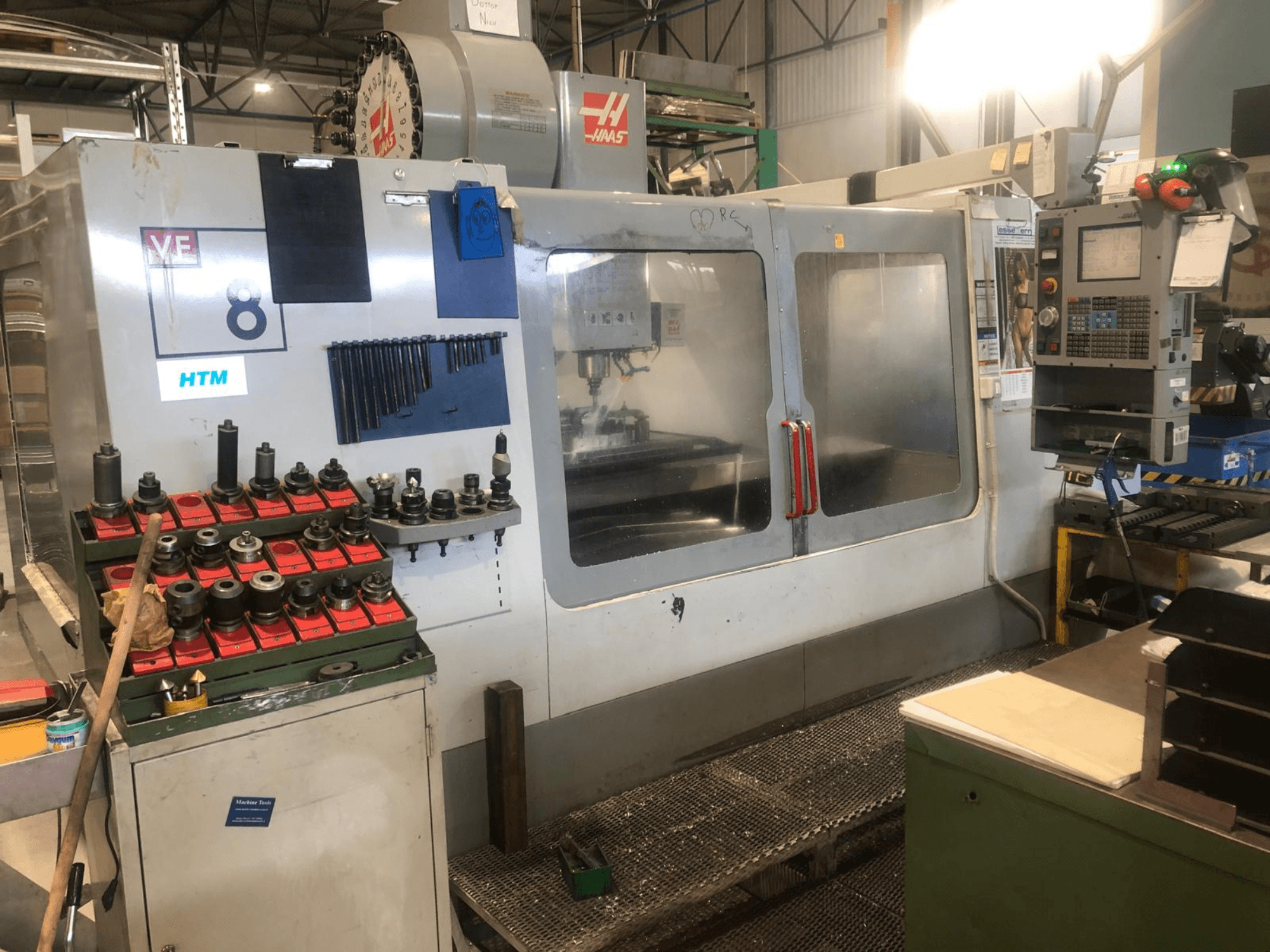 Machine CNC Haas dans un atelier, vue de face ; elle présente les outils et les commandes, avec des détails de modèle visibles et des porte-outils organisés.