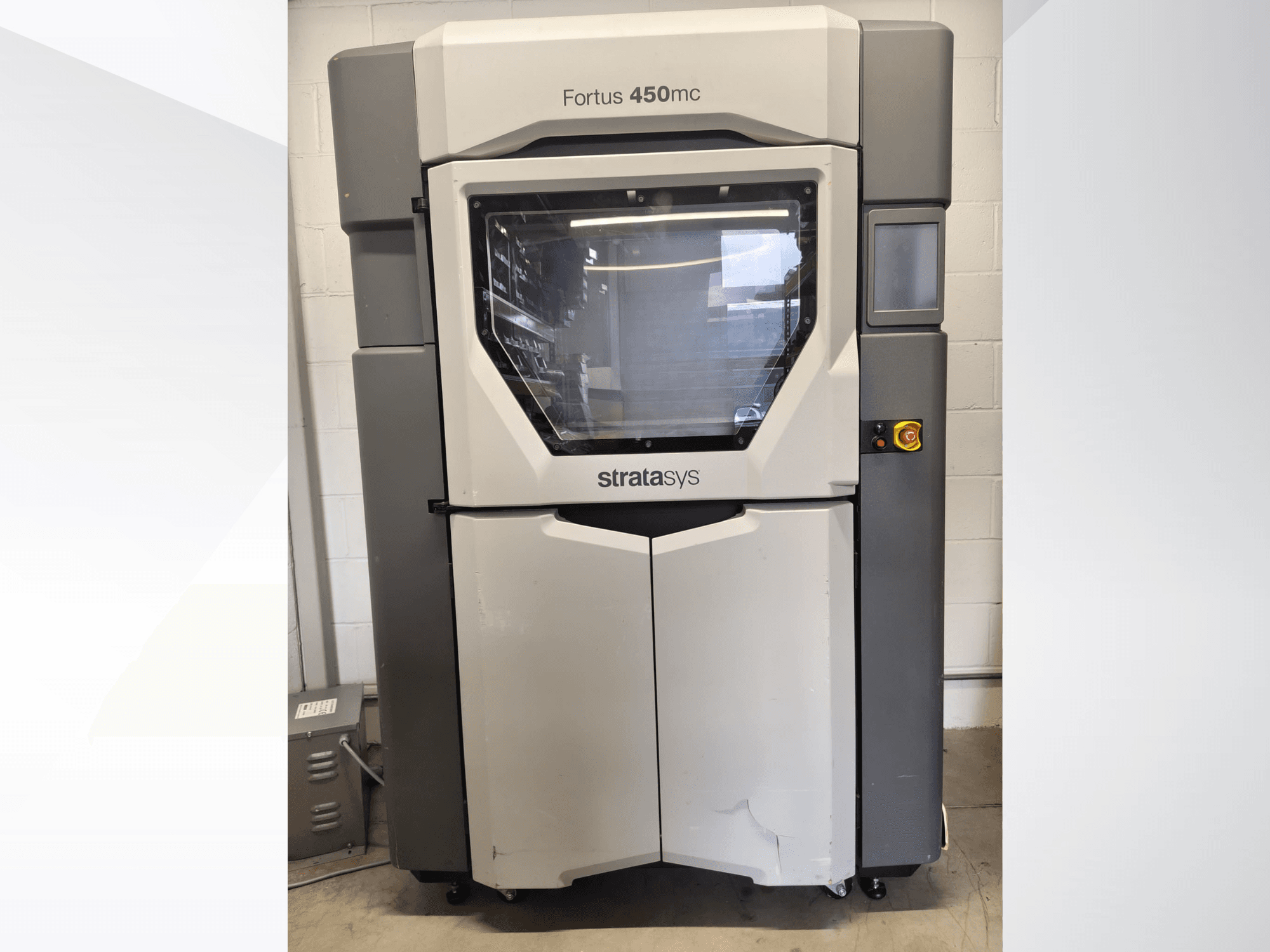 Machine de traitement des plastiques Stratasys Fortus 450mc, vue de face, dotée d'une grande vitre, d'un panneau de commande et d'un design industriel.
